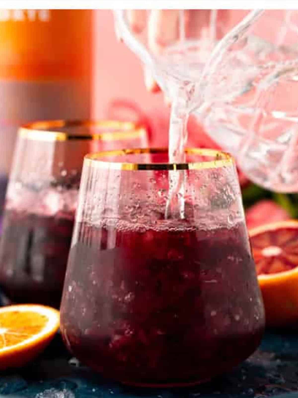 Club soda being topped into the red wine over ice.