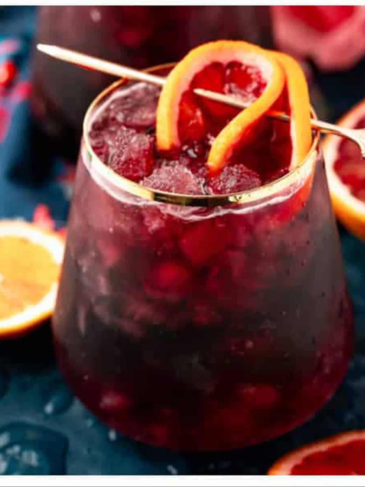 A finished red wine spritzer garnished with a fresh orange slice.