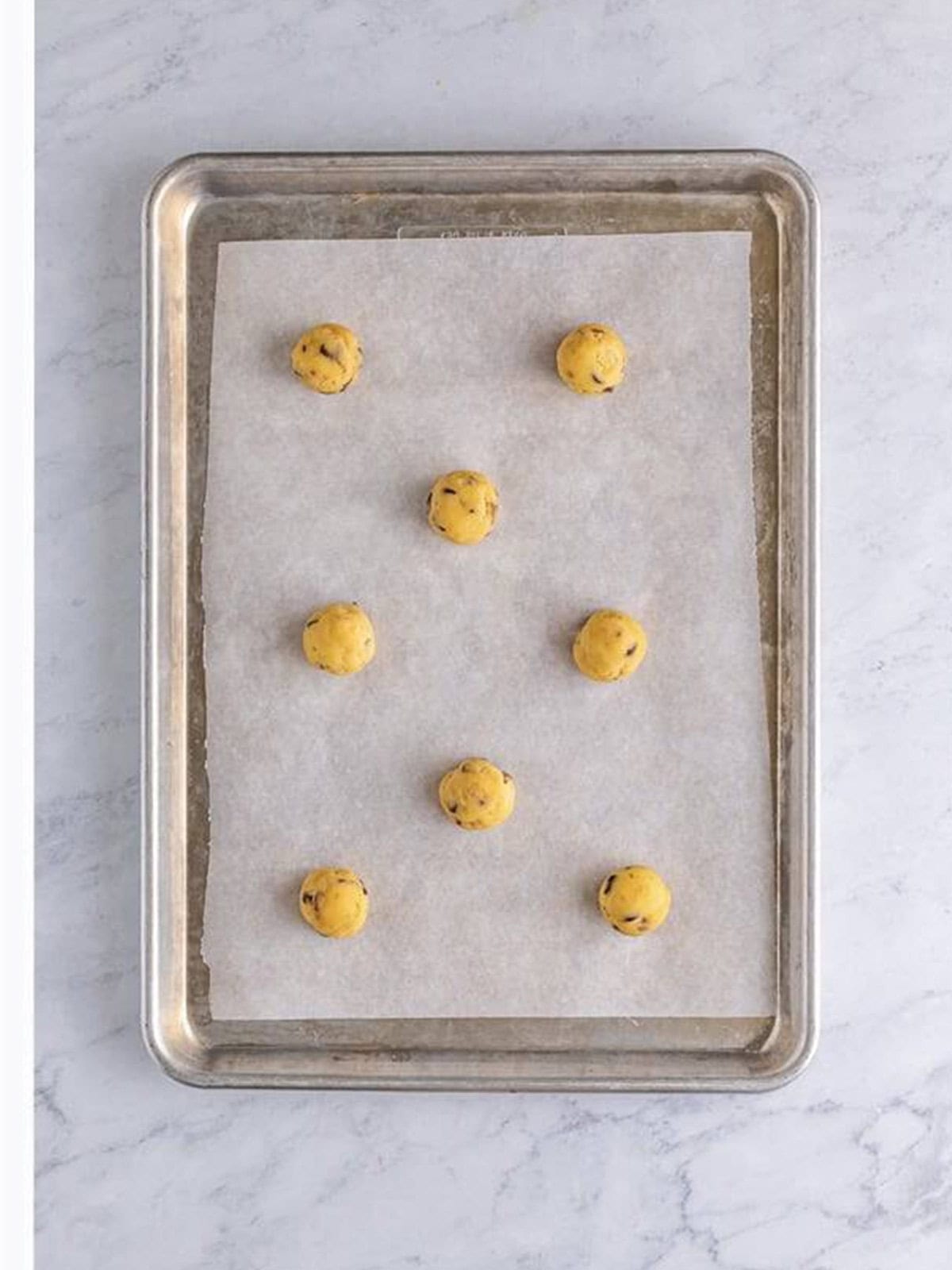 Chilled dough balls rolled and spaced two inches apart on a baking sheet.