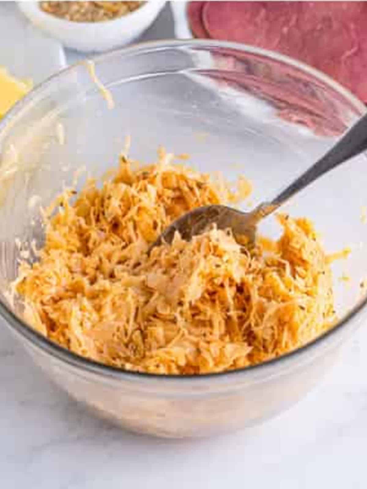 Sauerkraut mixed with Russian dressing and caraway seeds in a glass bowl.