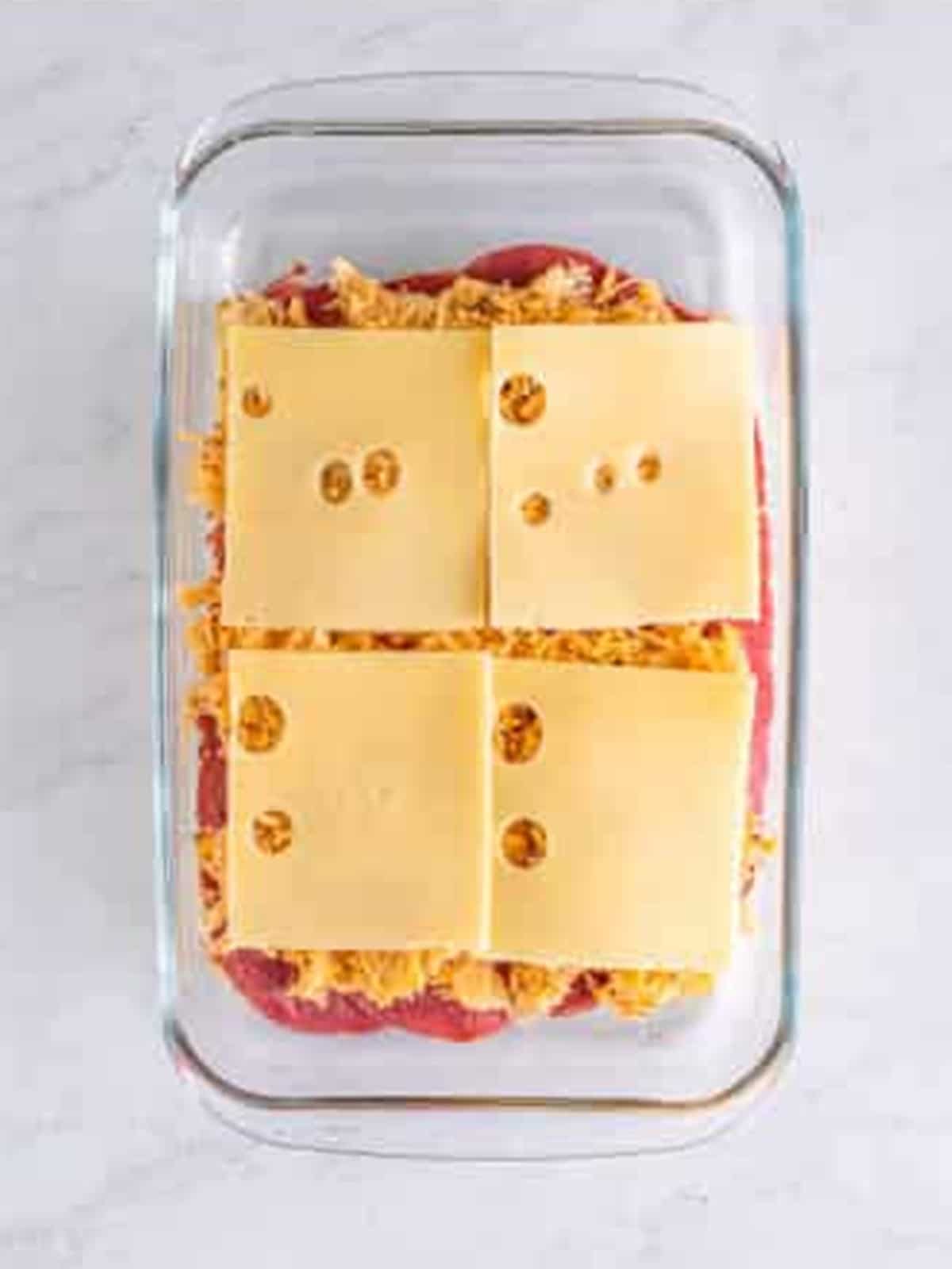 Sauerkraut and more swiss cheese layered on top of corned beef for reuben sliders.
