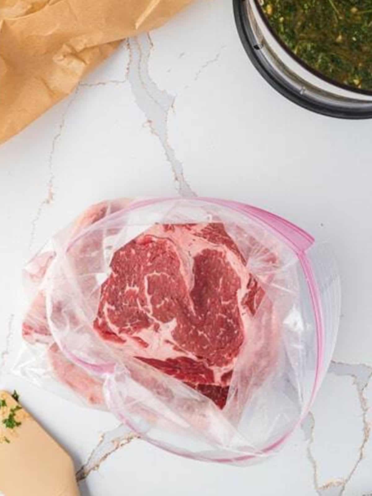 A raw ribeye steak placed in a ziplock bag.