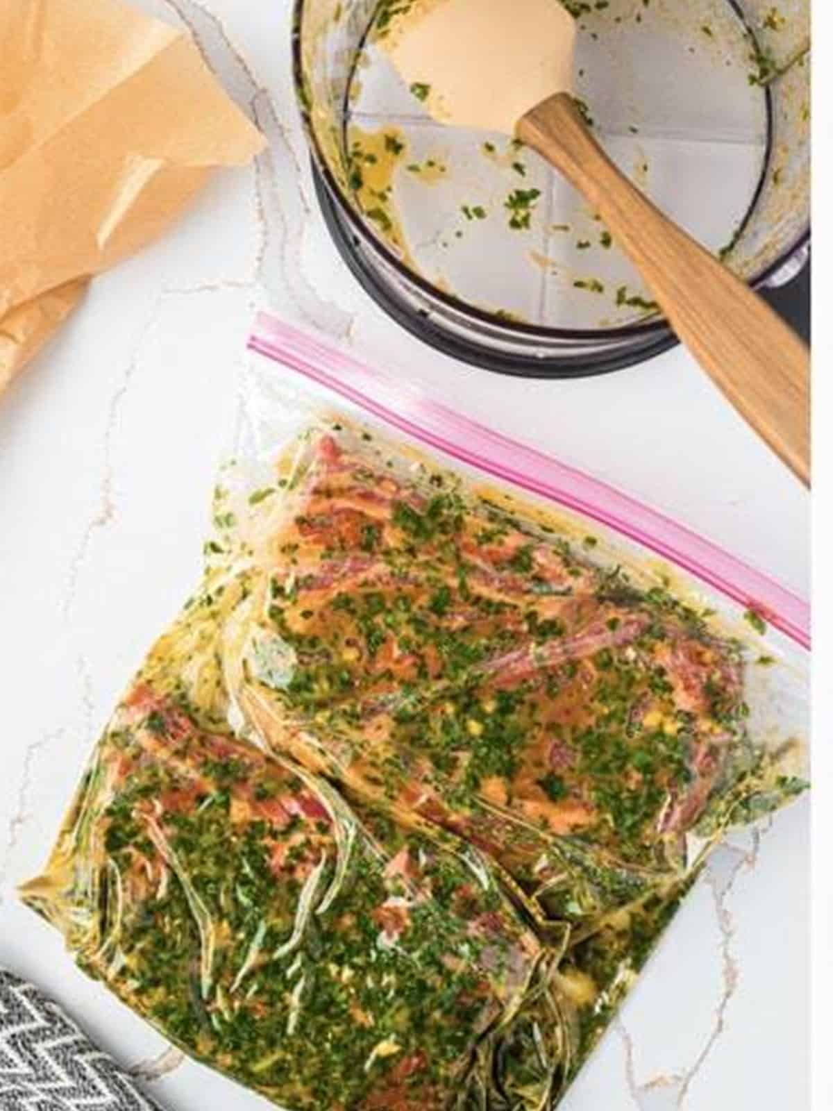 Ribeye steaks coated in cilantro lime marinade in a sealed bag.