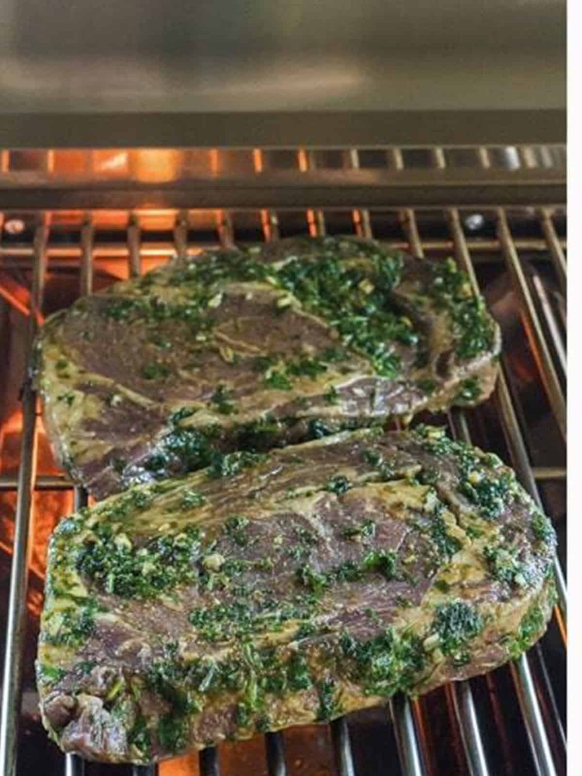 Marinated ribeye steaks cooking on a hot grill.