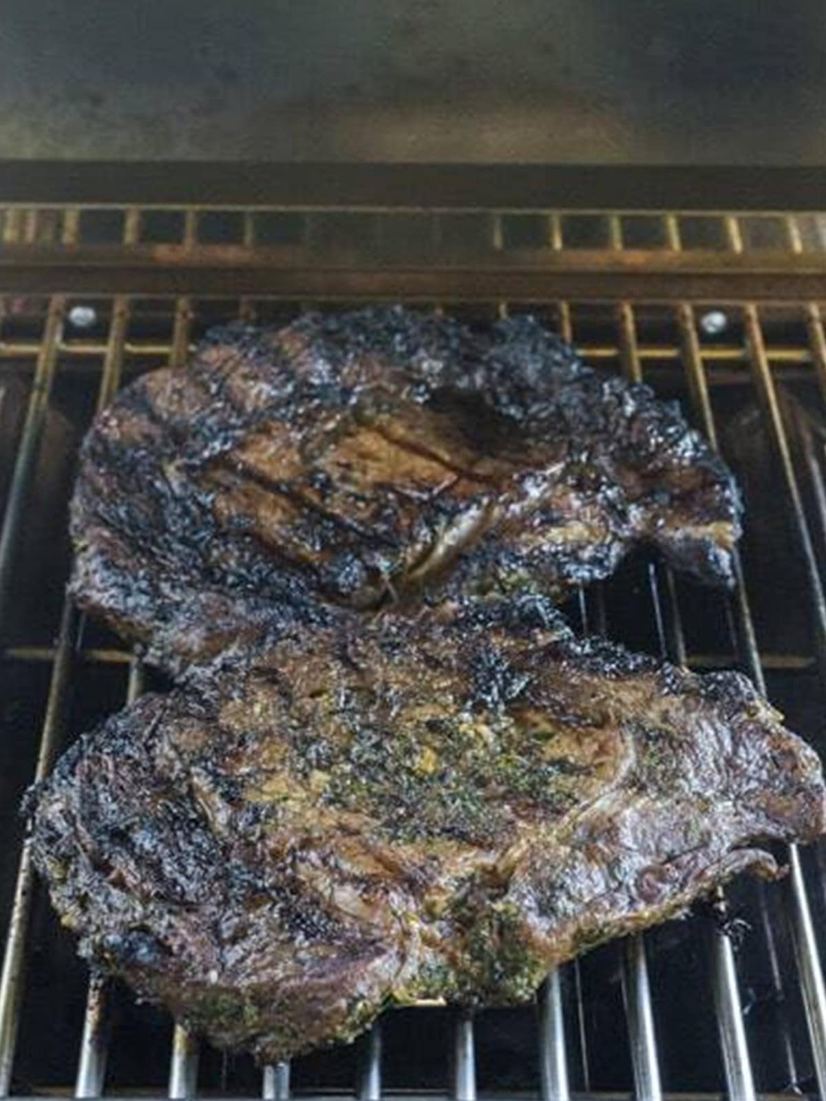 Grilled ribeye steaks resting on the grill grates.