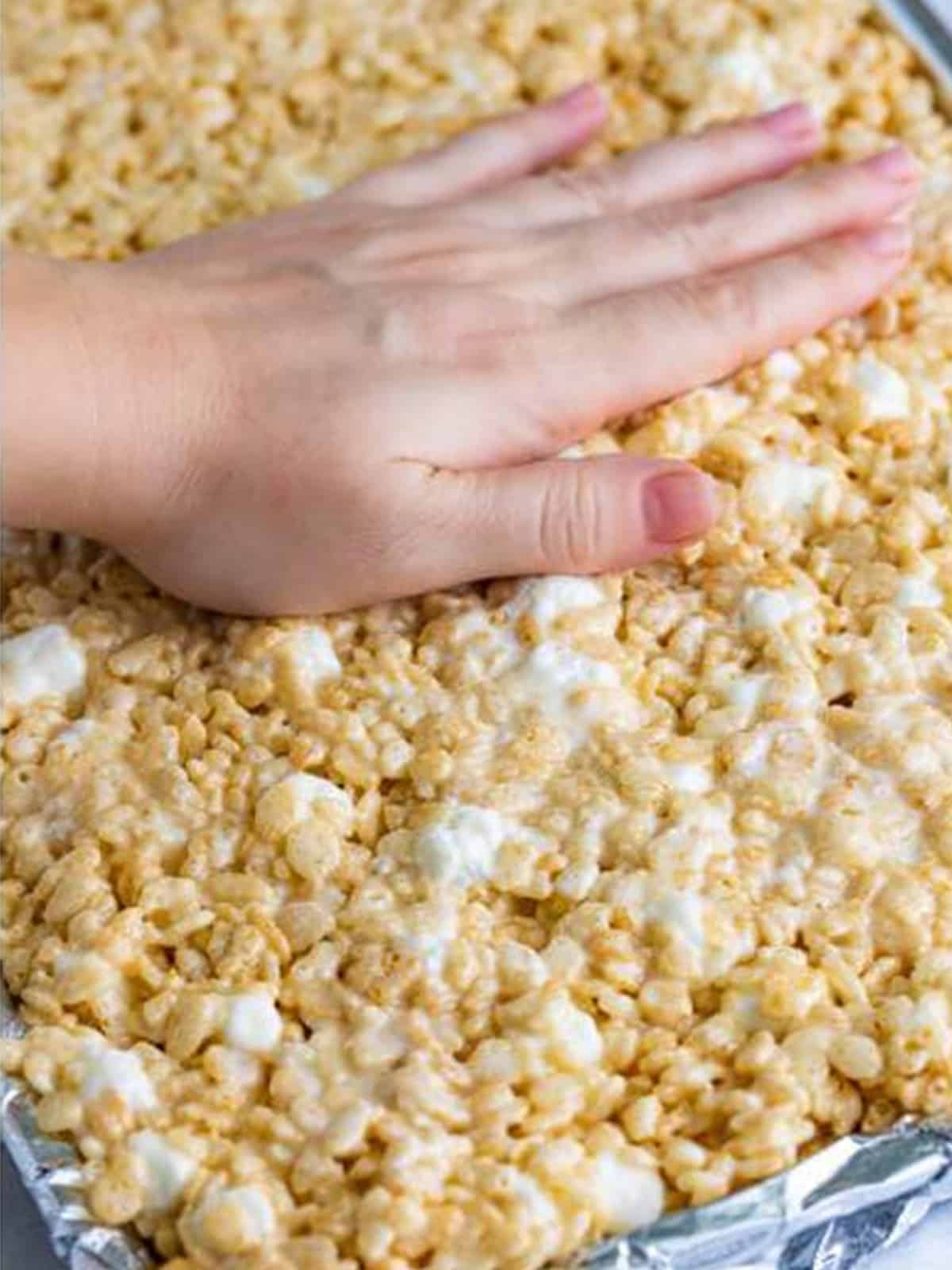 Rice Krispie Treats mixture gently pressed into a lined pan.