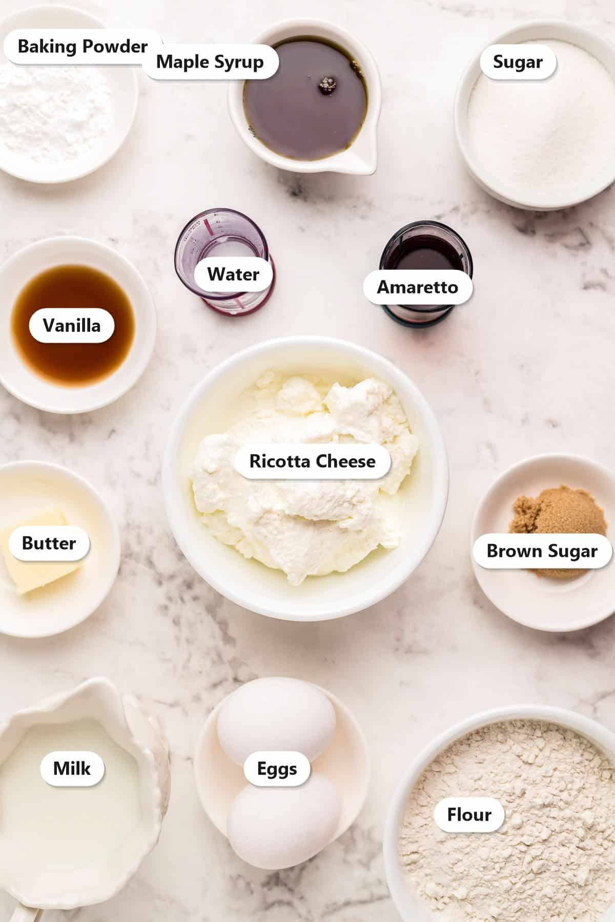 Labeled ingredients for ricotta pancakes including ricotta cheese, flour, eggs, milk, butter, and amaretto syrup ingredients.