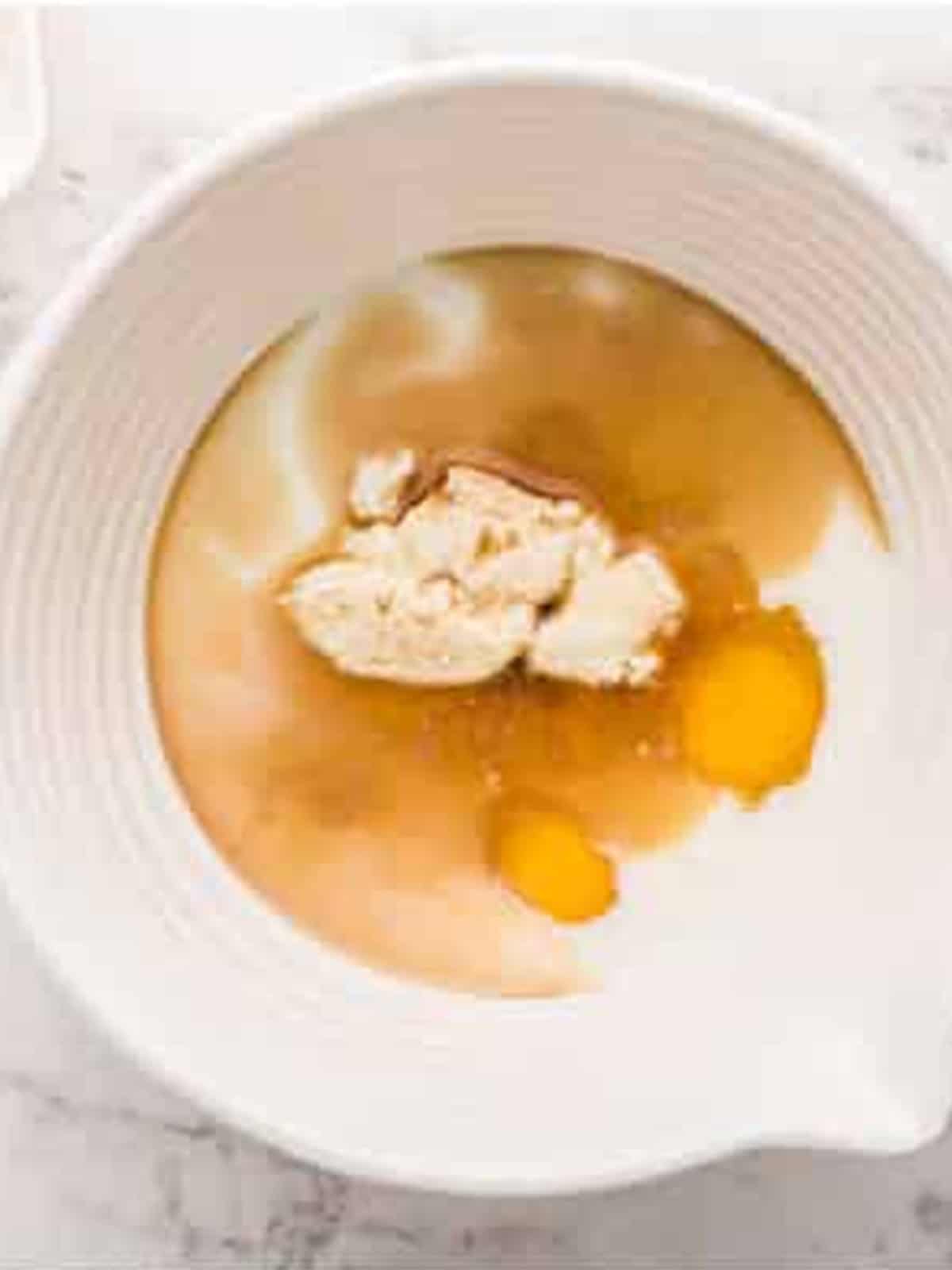 Ricotta cheese, milk, eggs, and vanilla in a mixing bowl.