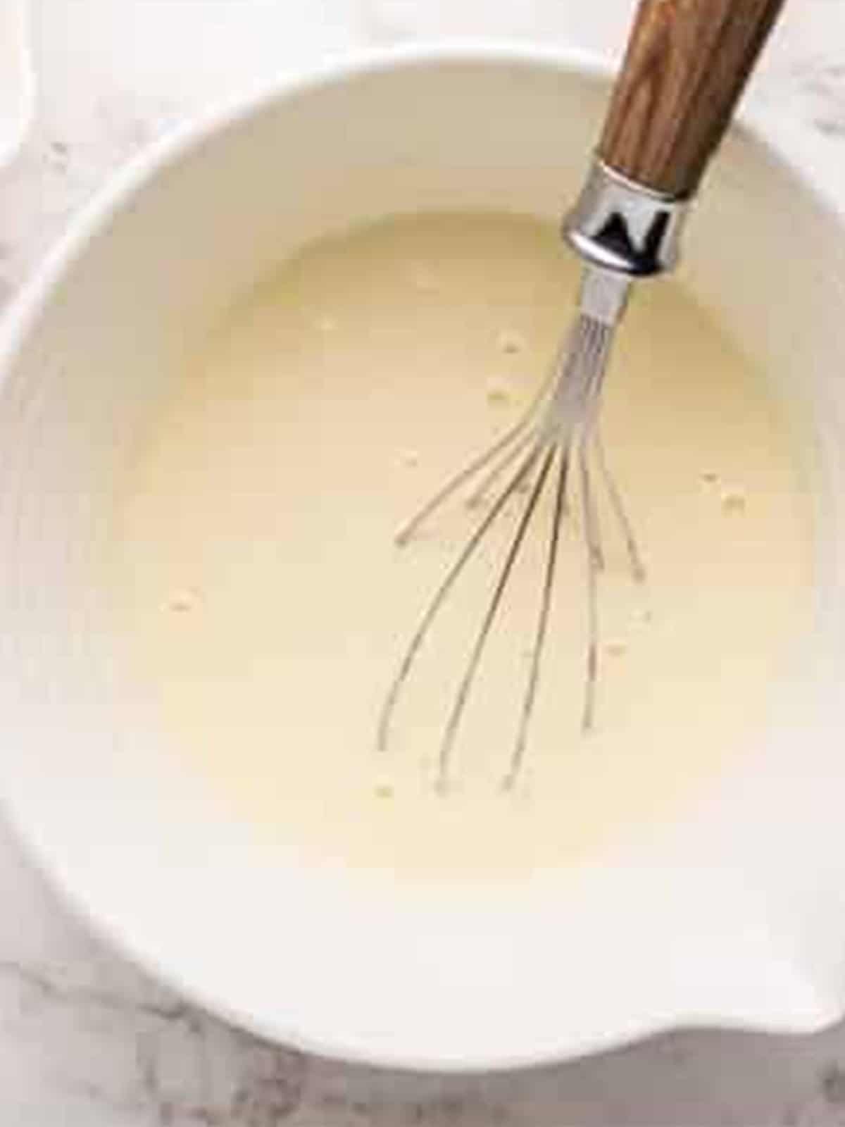 Smooth ricotta pancake batter whisked together in a bowl.