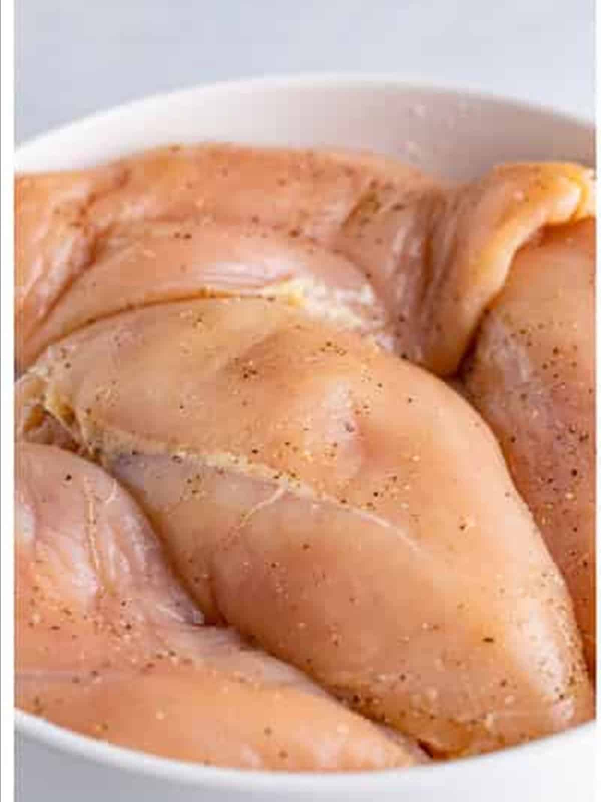 Seasoning raw chicken breasts for Ritz cracker chicken.