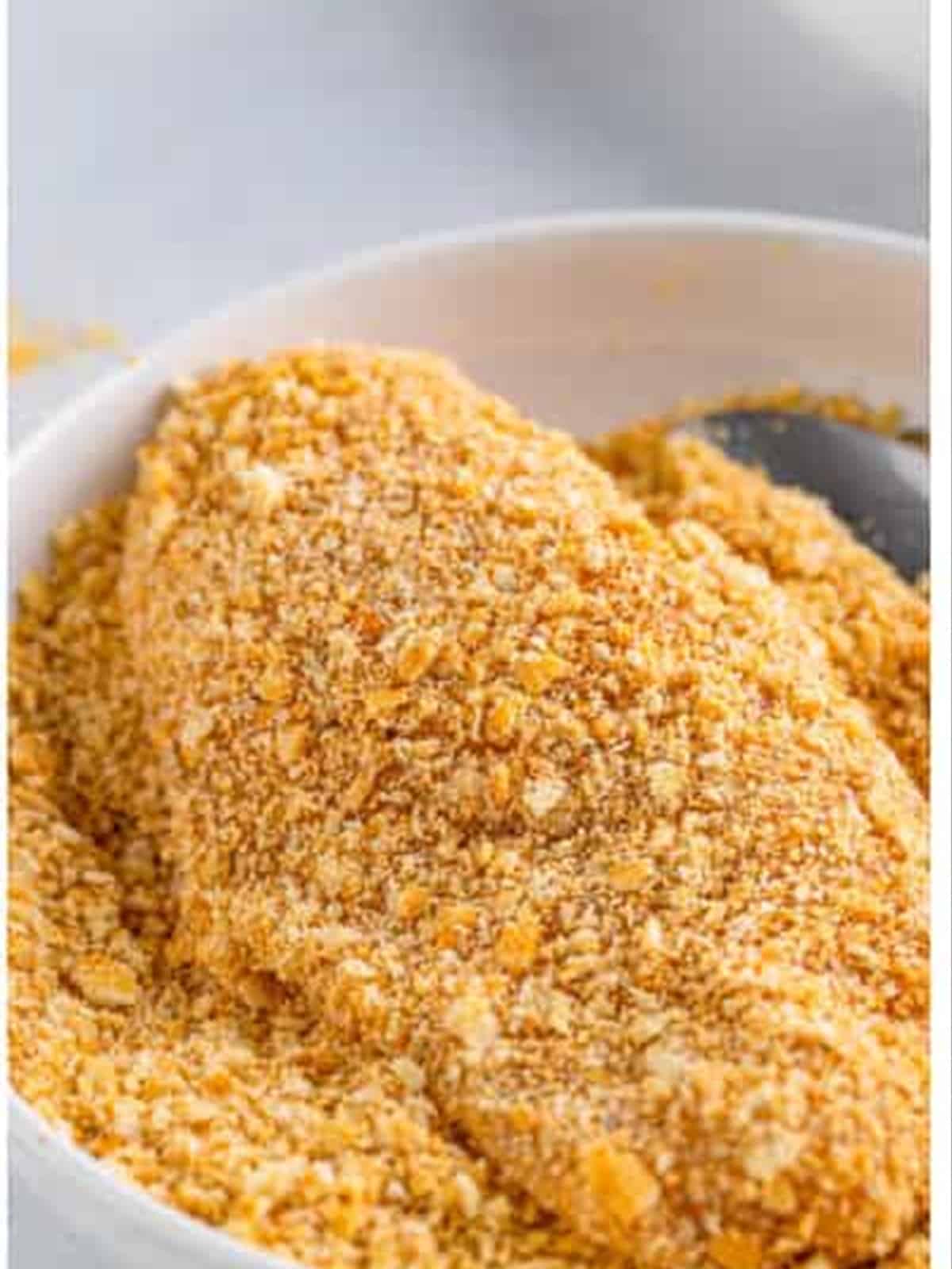 Coating chicken in the Ritz cracker crumbs.