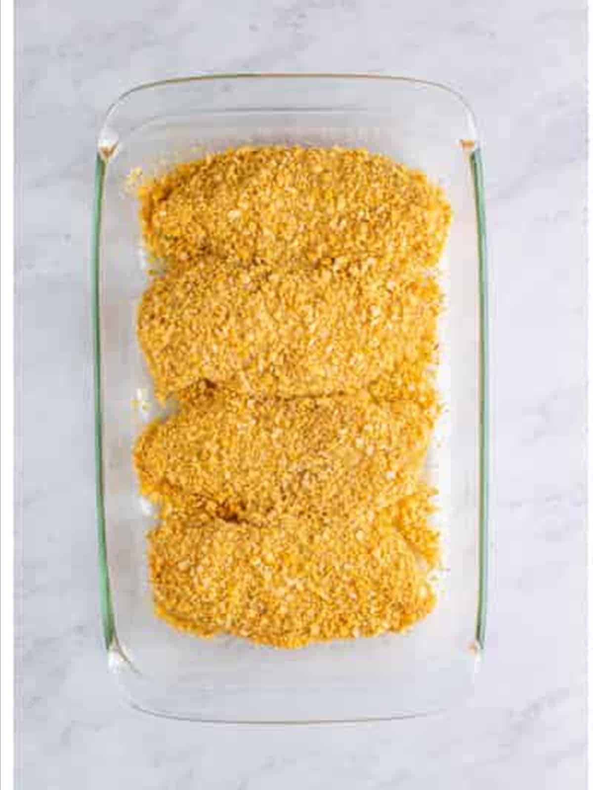 Coated chicken in a baking dish for Ritz cracker chicken.