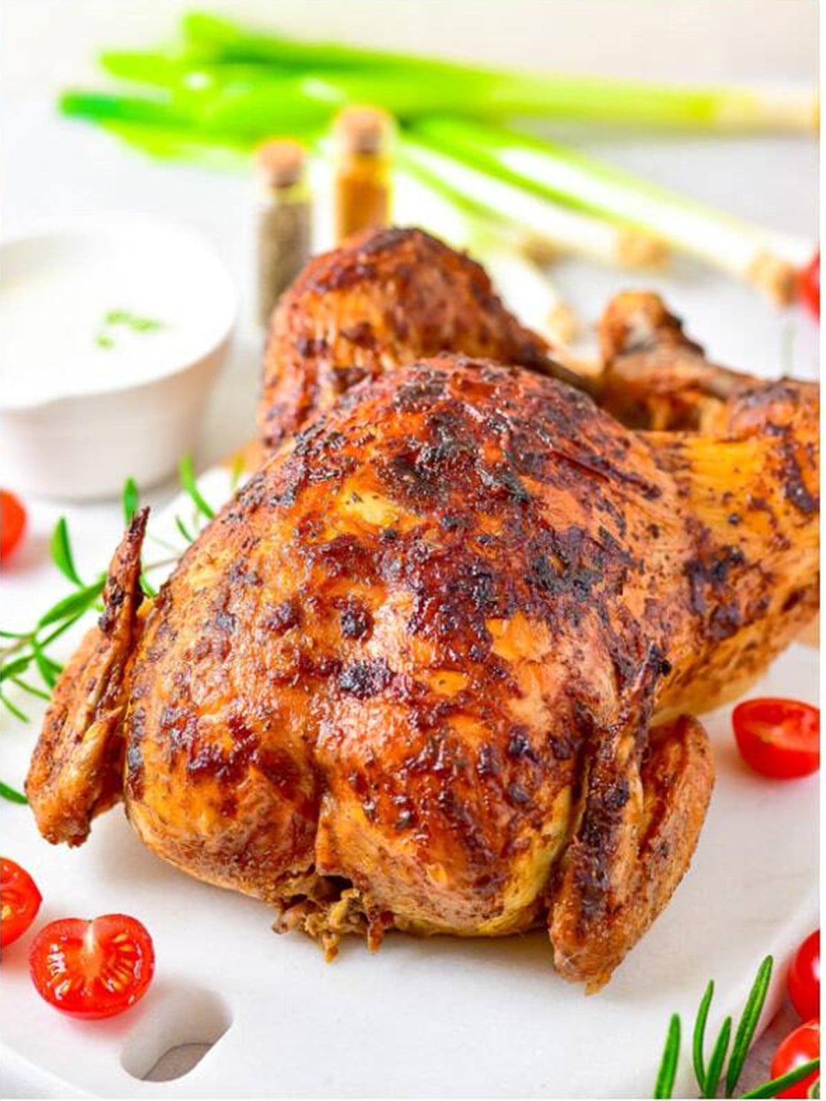 Golden brown roast chicken resting on a platter after roasting.
