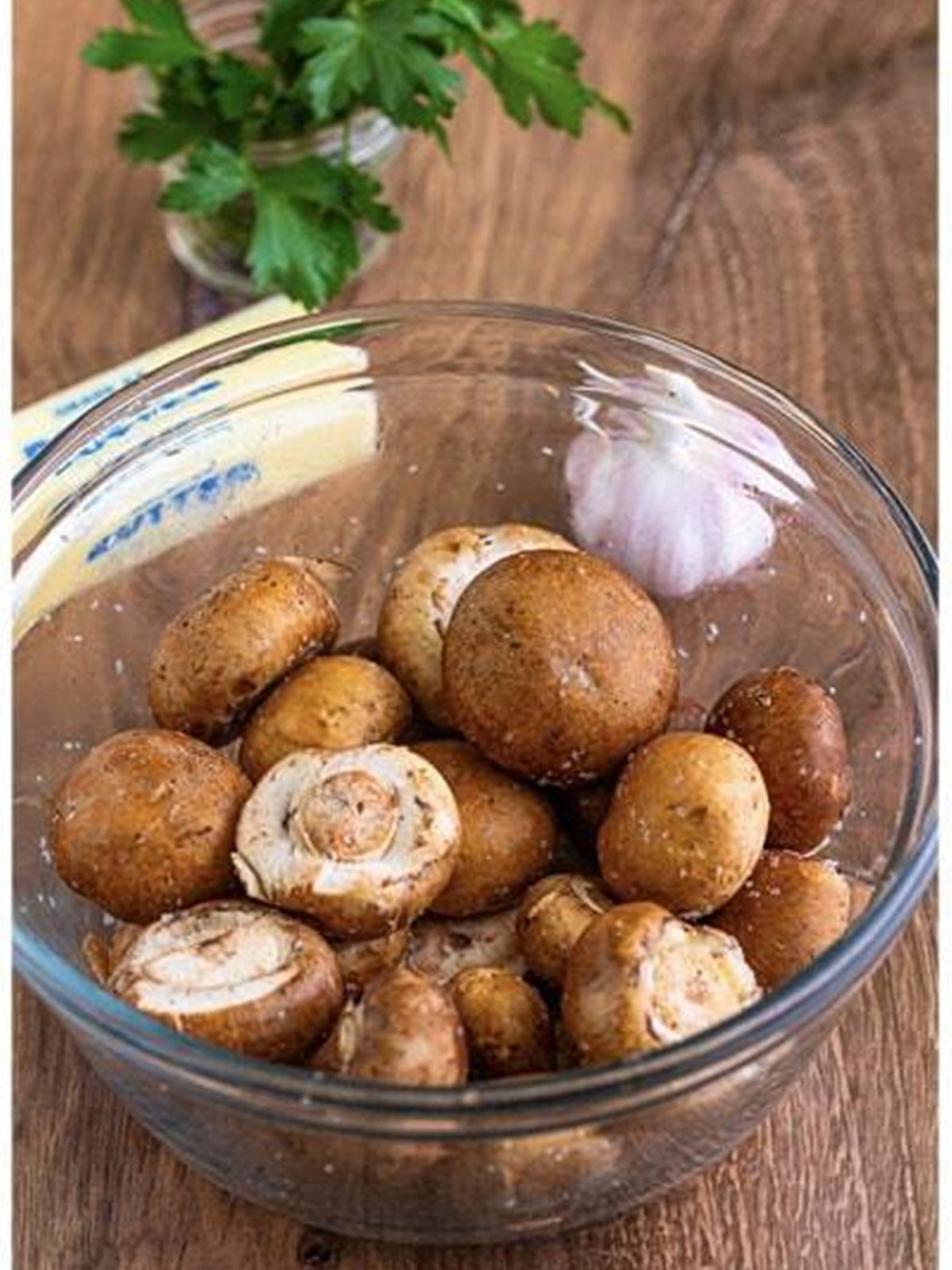 Mushrooms tossed with olive oil, salt, and pepper in a bowl.