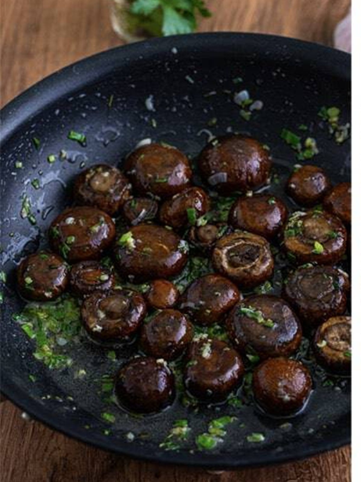 Mushrooms tossed in garlic butter sauce in a skillet.