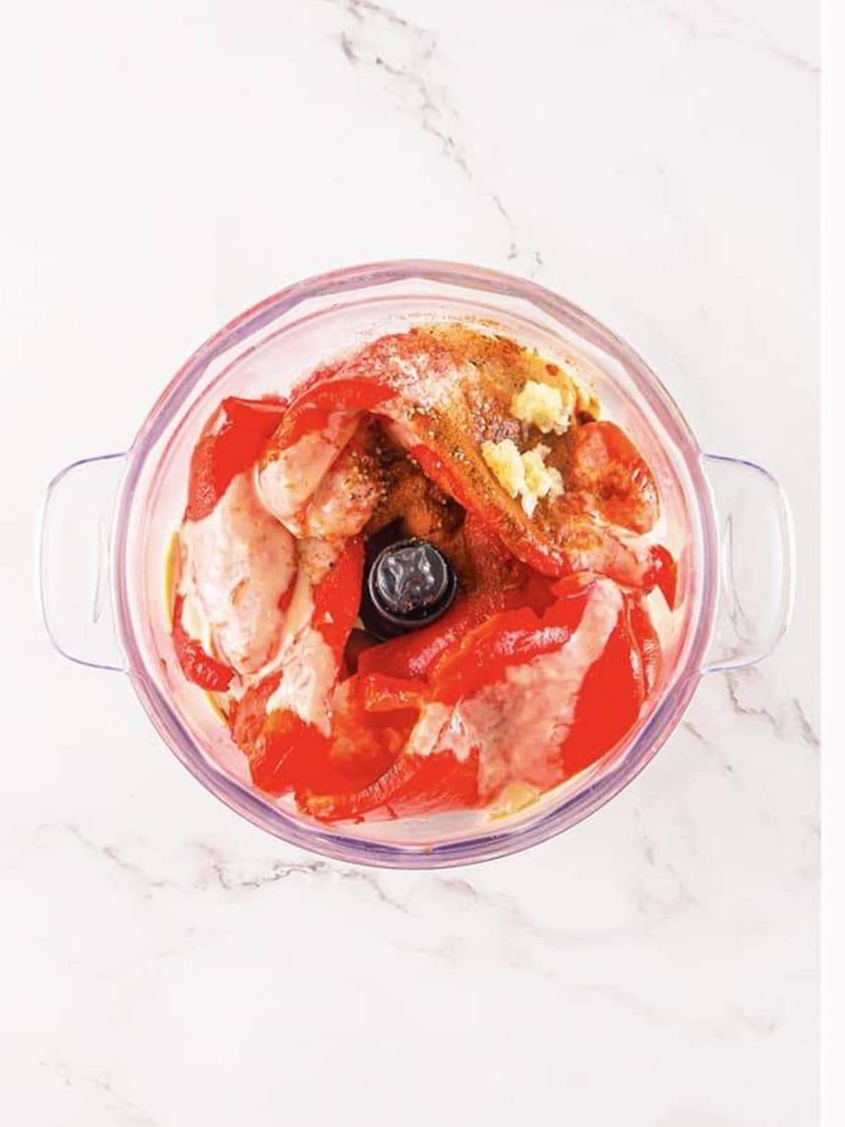 Peeled roasted red peppers, chickpeas, tahini, and seasonings added to a blender.