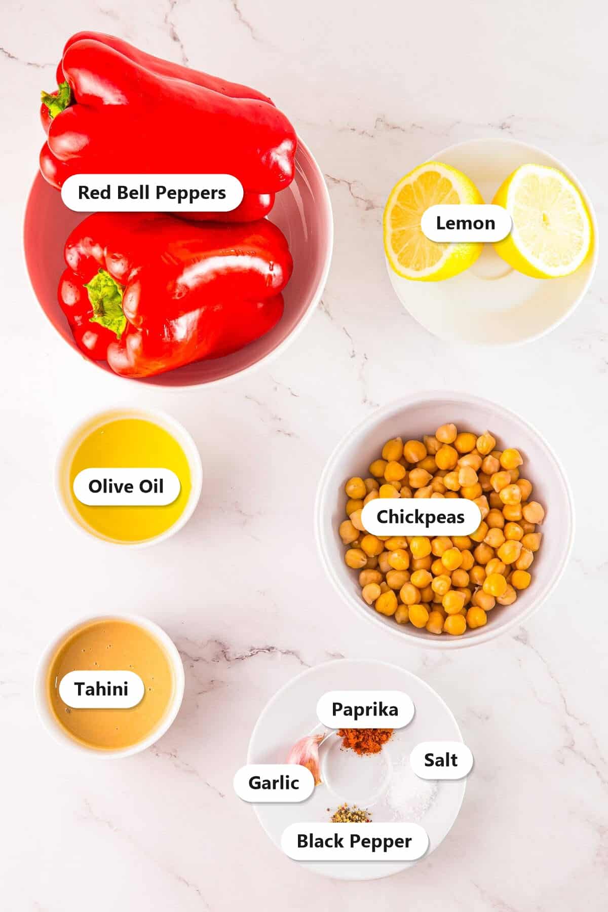 Labeled ingredients for roasted red pepper hummus including red bell peppers, chickpeas, tahini, lemon, olive oil, garlic, paprika, salt, and pepper.