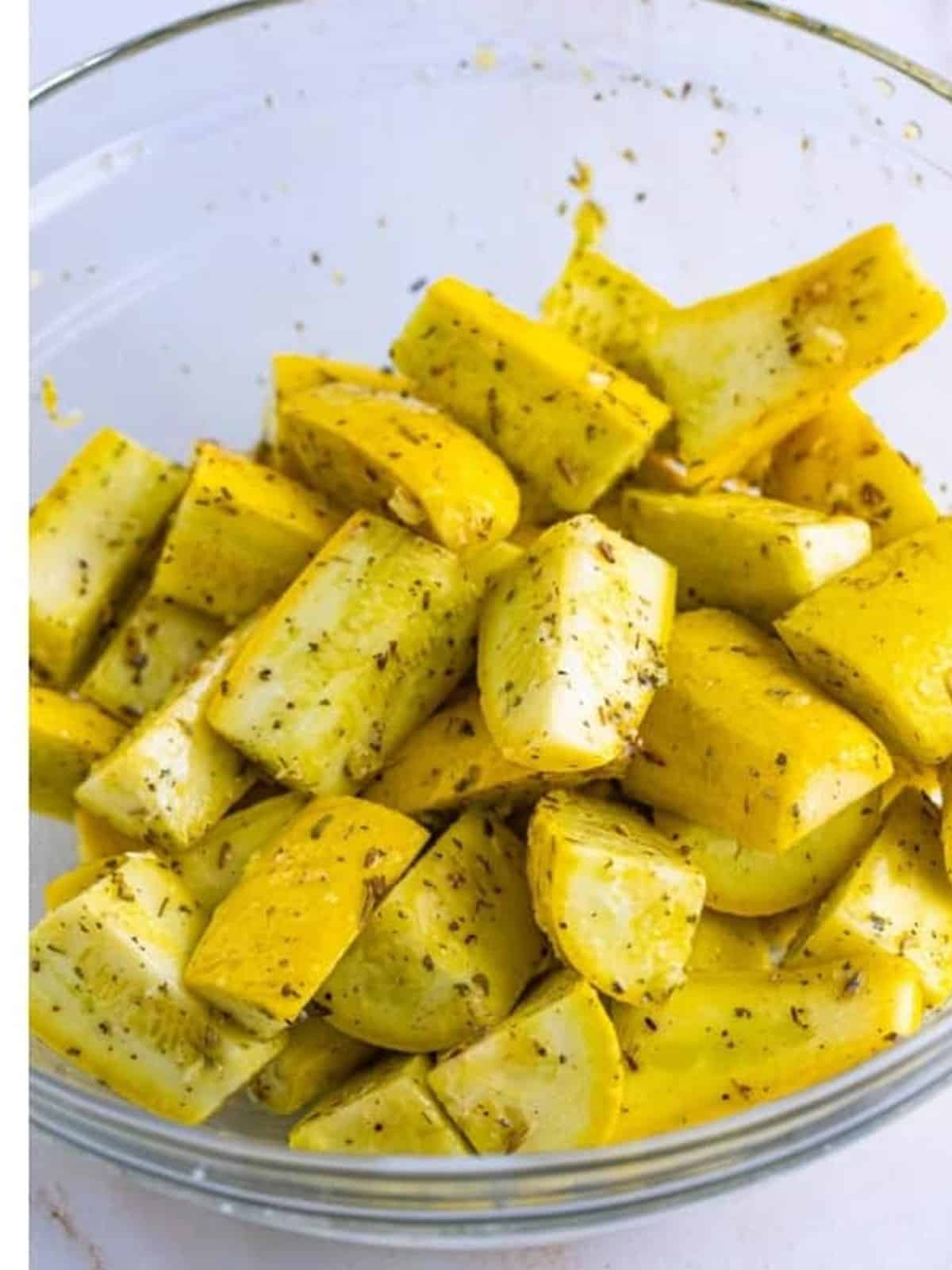 Yellow squash tossed until evenly coated in seasoning and olive oil.