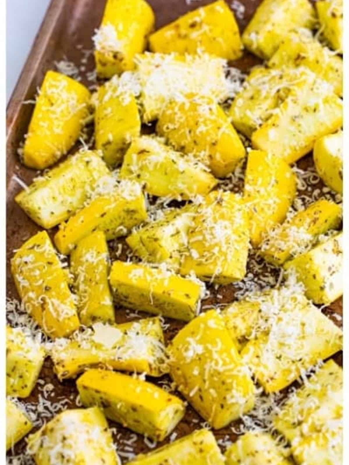 Freshly grated parmesan sprinkled over yellow squash on the sheet tray before roasting.