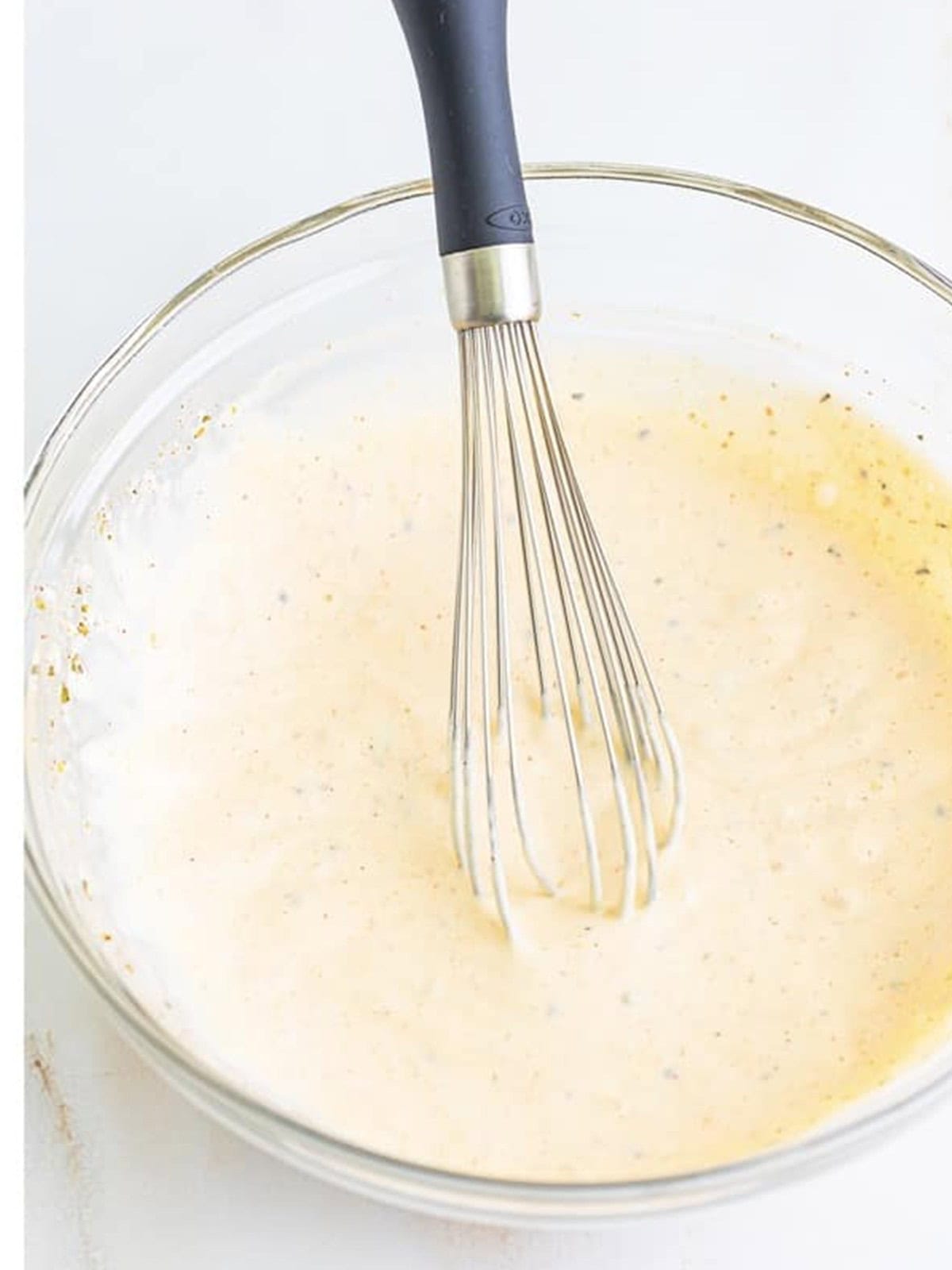 Creamy dressing for rotisserie chicken salad whisked together in a glass bowl.