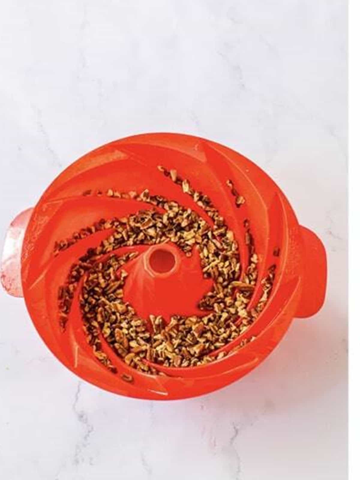 Chopped pecans sprinkled in the bottom of a greased bundt pan.