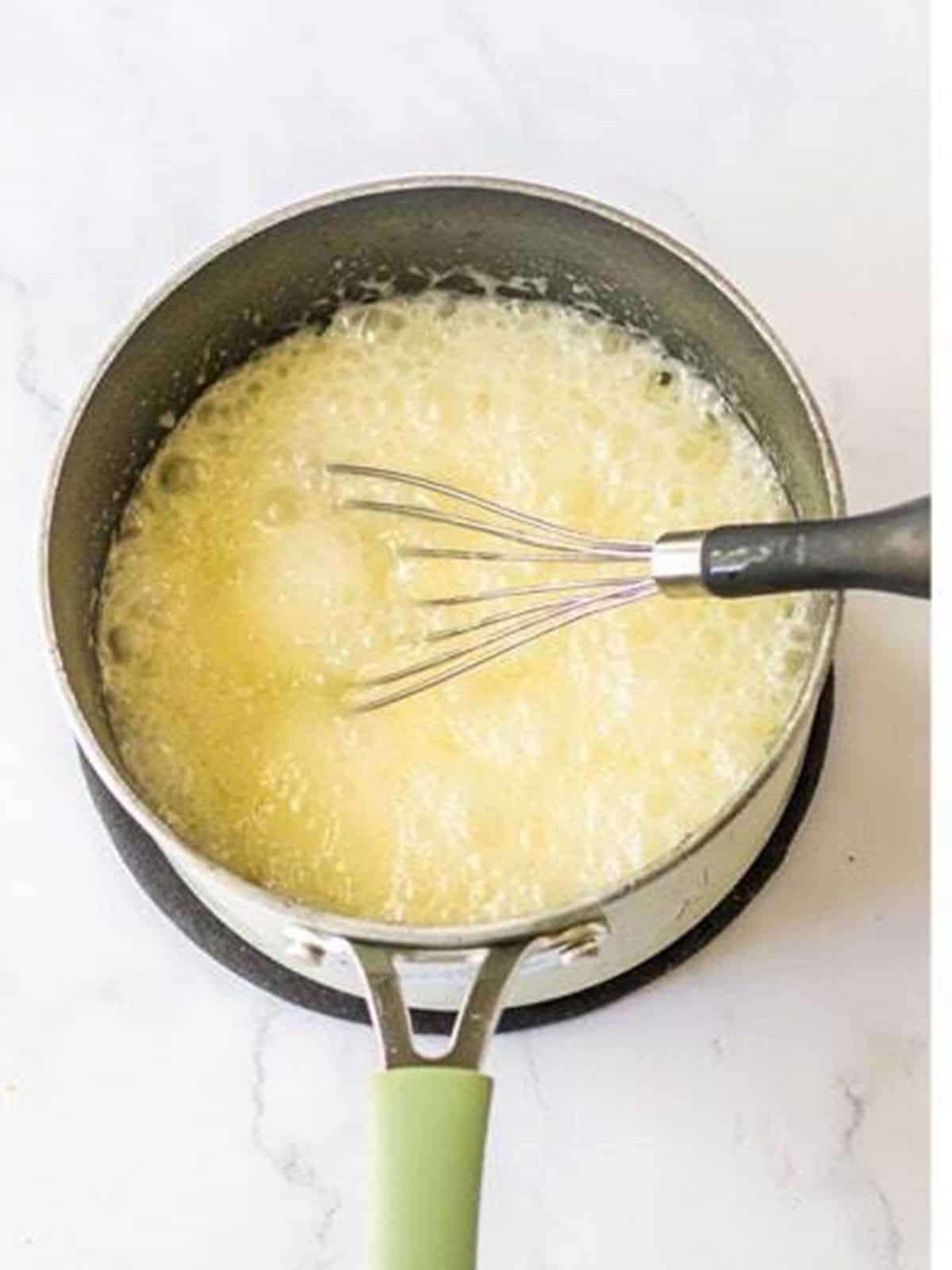 Butter, sugar, water, and rum glaze cooking in a saucepan.