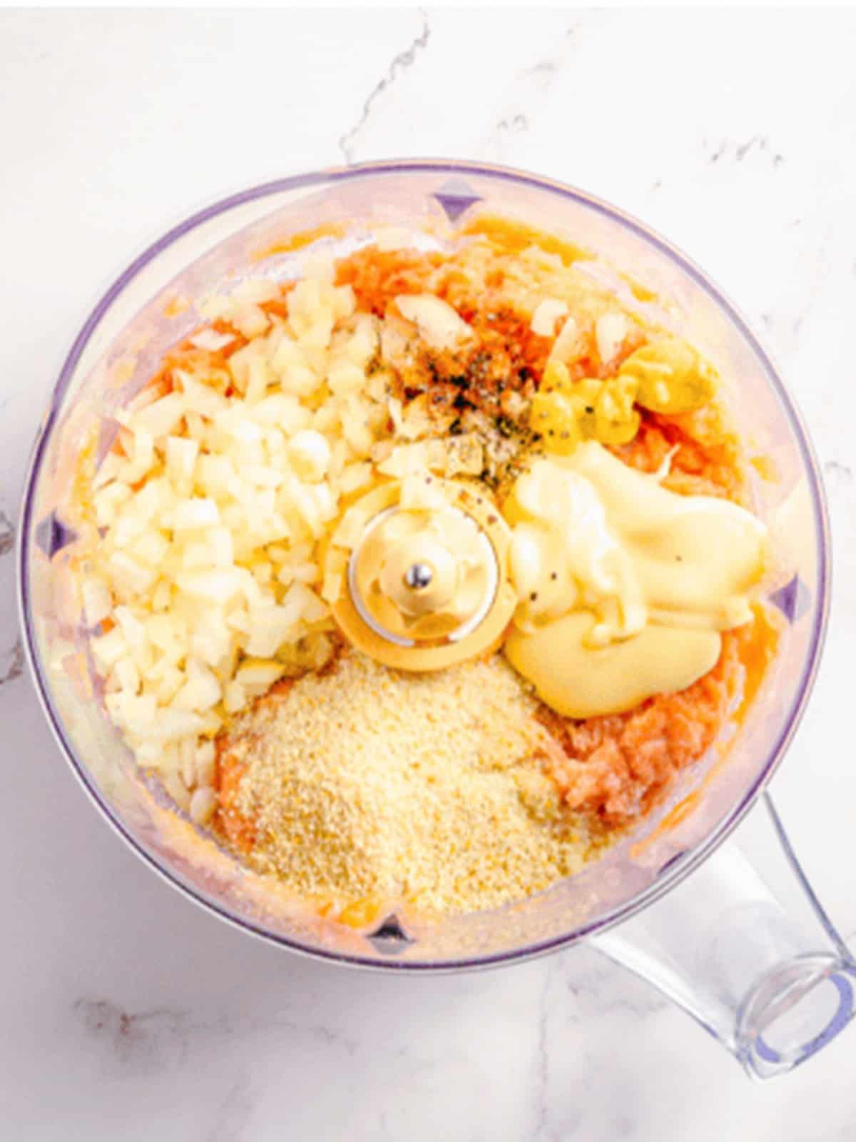 Adding mayonnaise, breadcrumbs, onion, and seasonings to the processed salmon.
