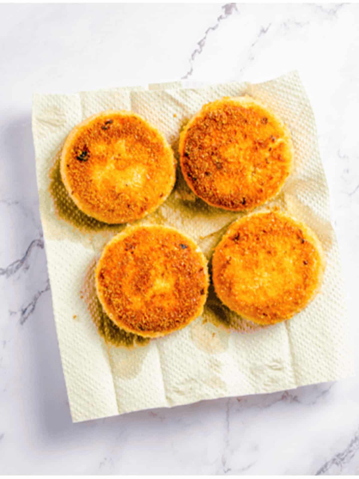 Crispy golden salmon burger patties draining on a paper towel.