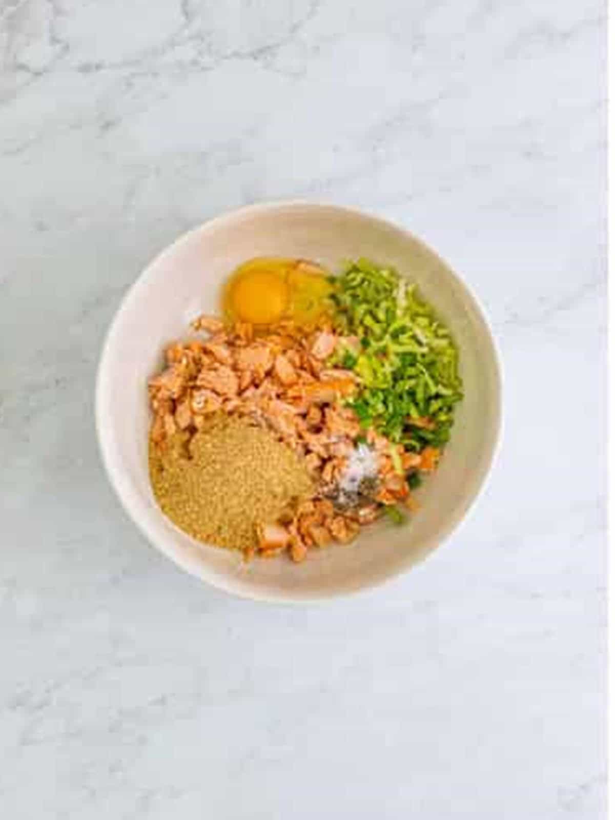 Salmon, egg, breadcrumbs, scallions, and seasonings combined in a bowl to make salmon patties recipe.