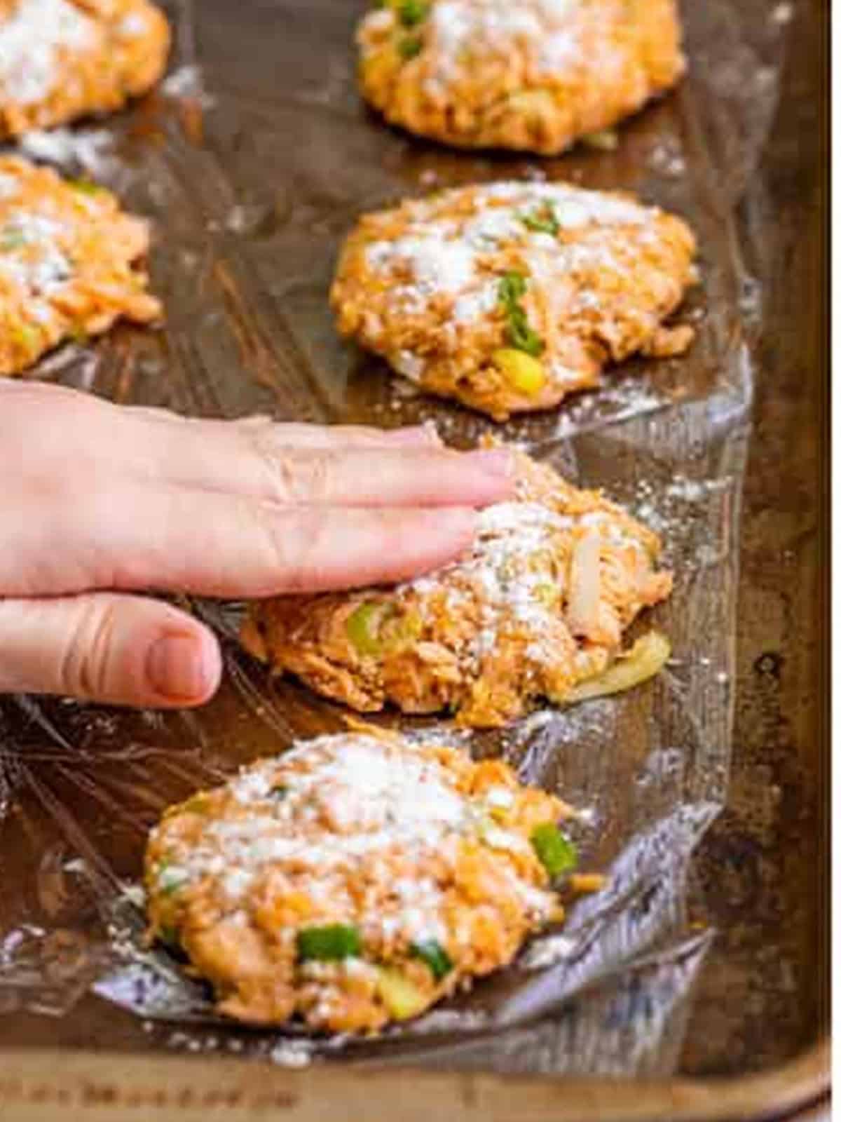 Salmon patties dusted with flour on a tray before pan frying.