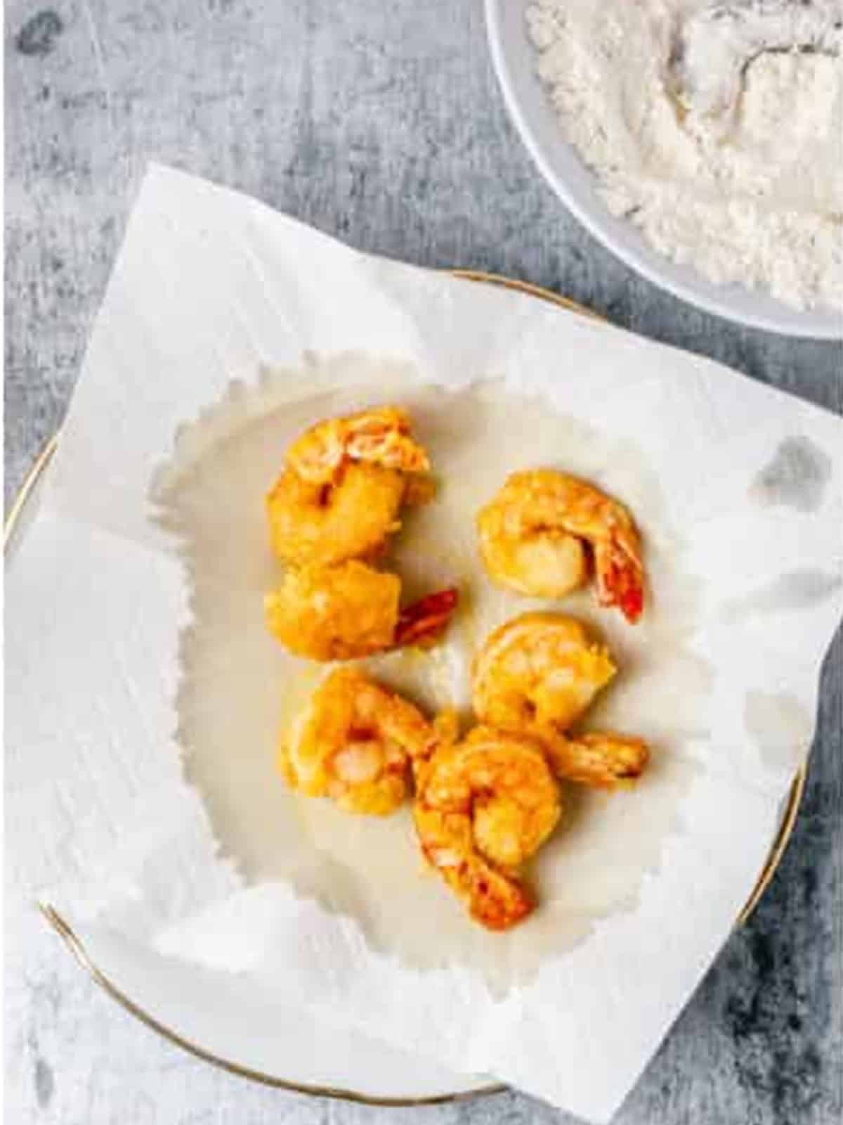 Crispy fried shrimp draining on a paper towel.