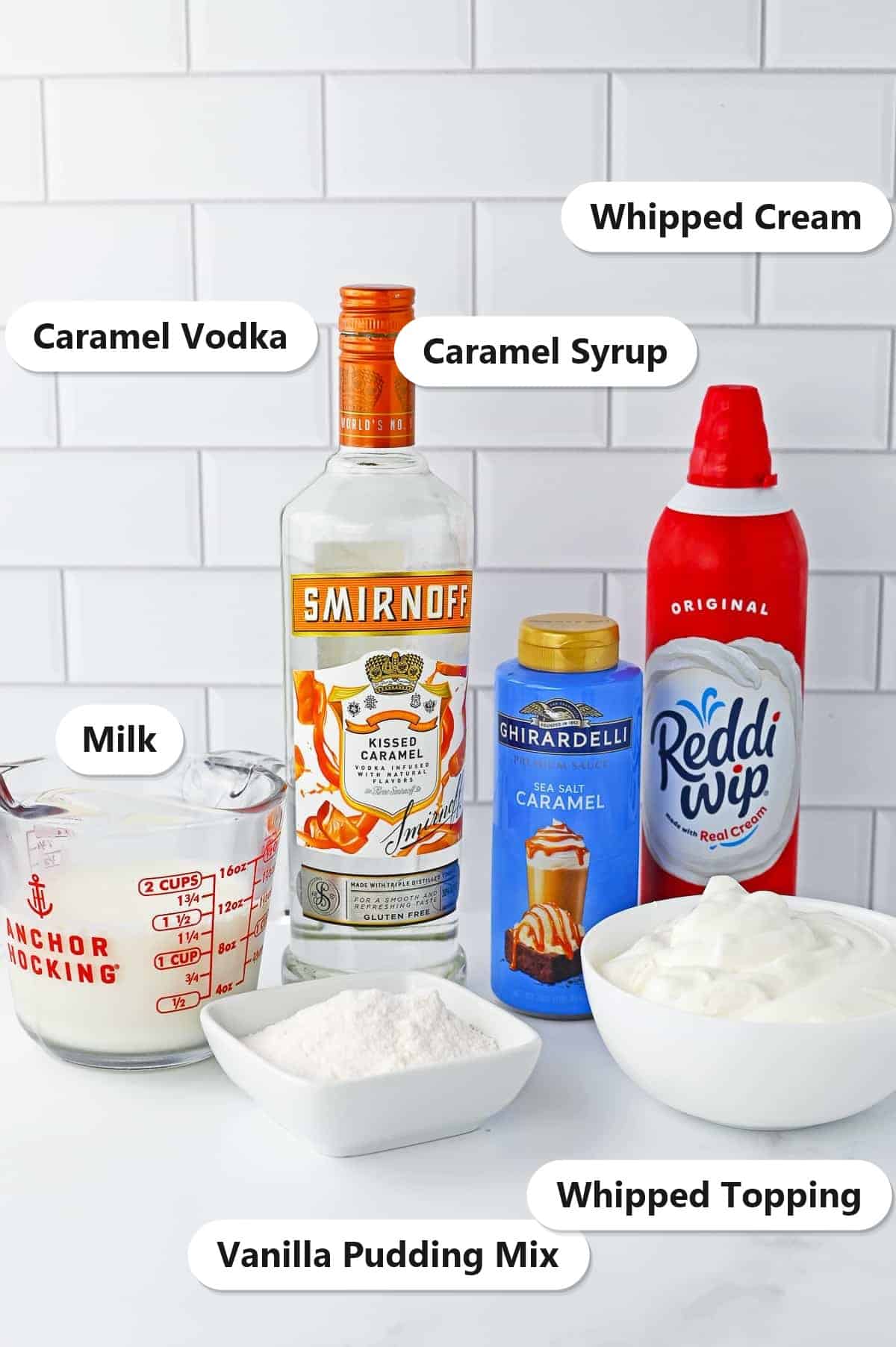 Labeled ingredients for salted caramel pudding shots including vanilla pudding mix, milk, caramel vodka, salted caramel syrup, whipped topping, and whipped cream.