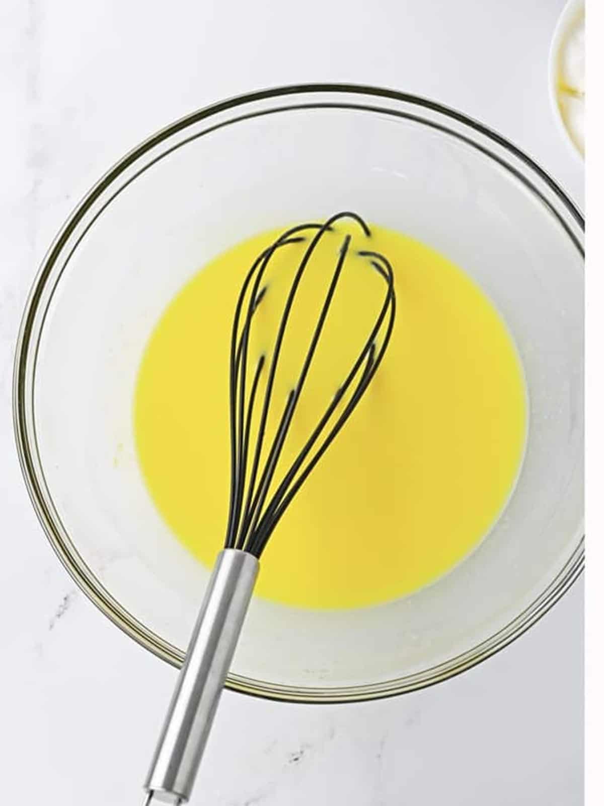 Vanilla pudding mix and milk whisked together in a glass bowl for salted caramel pudding shots.