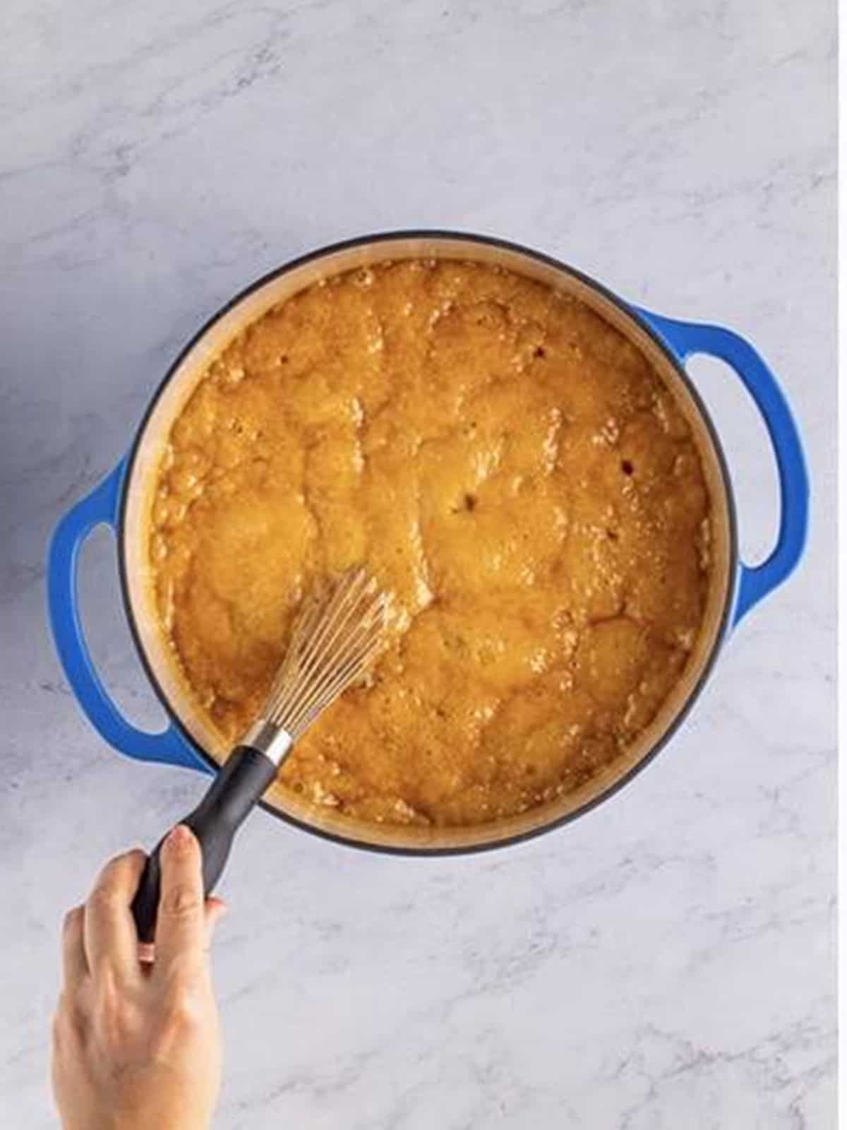 The salted caramel mixture boiling and being stirred in a pot.