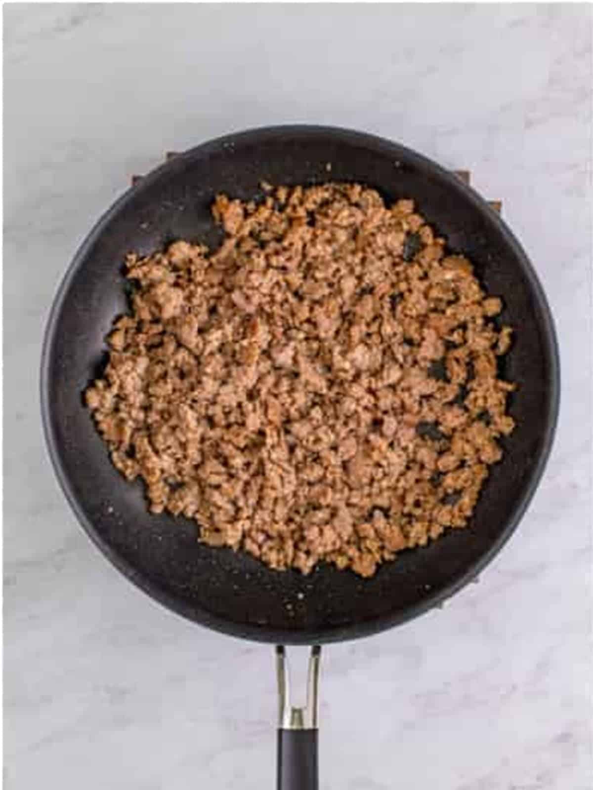 Browned and crumbled pork sausage in a skillet for sausage pinwheels.