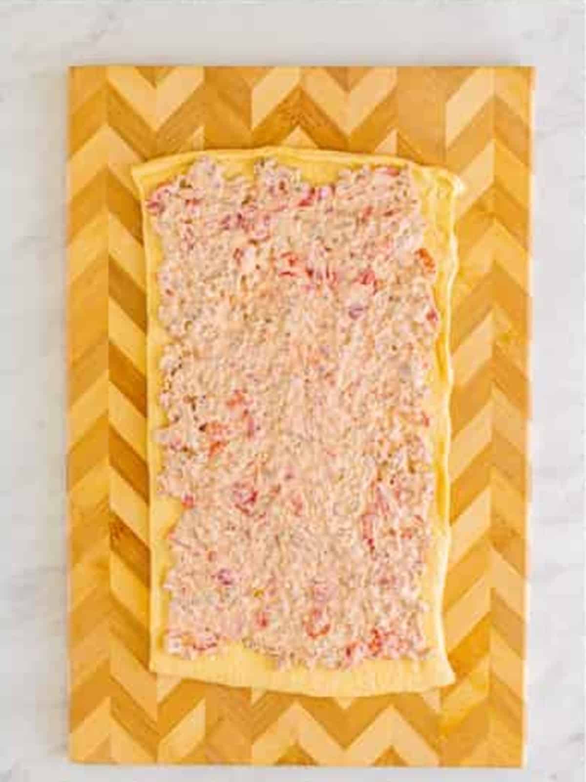 Sausage dip spread over crescent dough for sausage pinwheels.