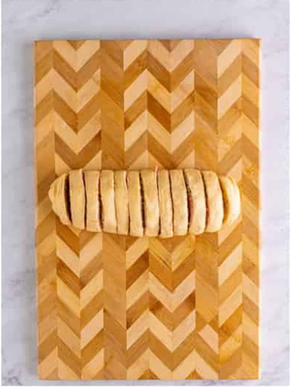 A rolled crescent dough log sliced into sausage pinwheels.
