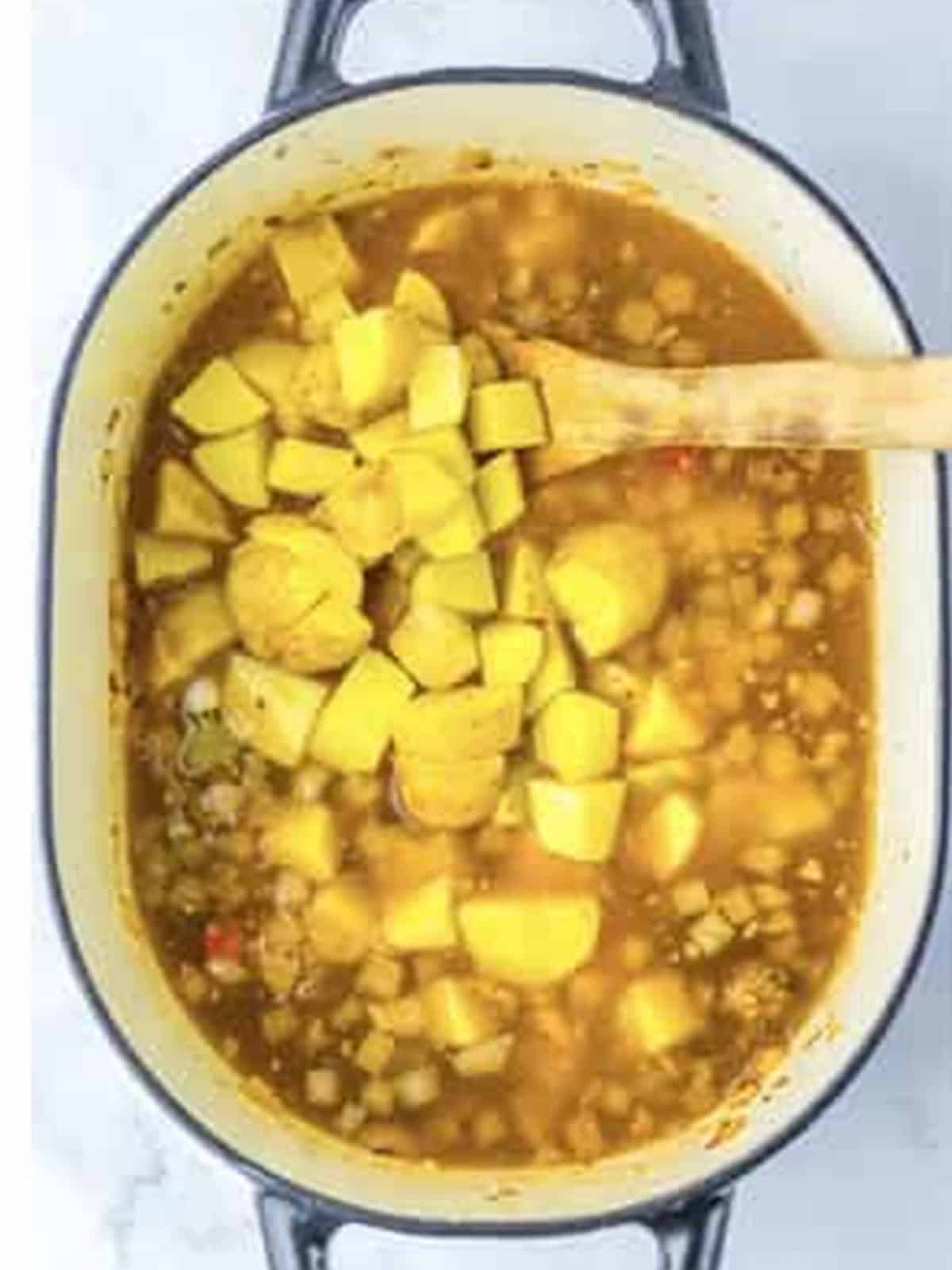 Yellow potato chunks and vegetable broth added to the soup pot.