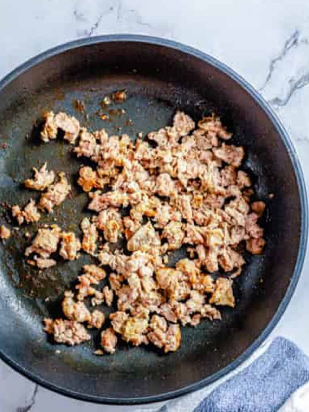 Ground pork sausage browned and crumbled in a skillet for sausage stuffed mushrooms.