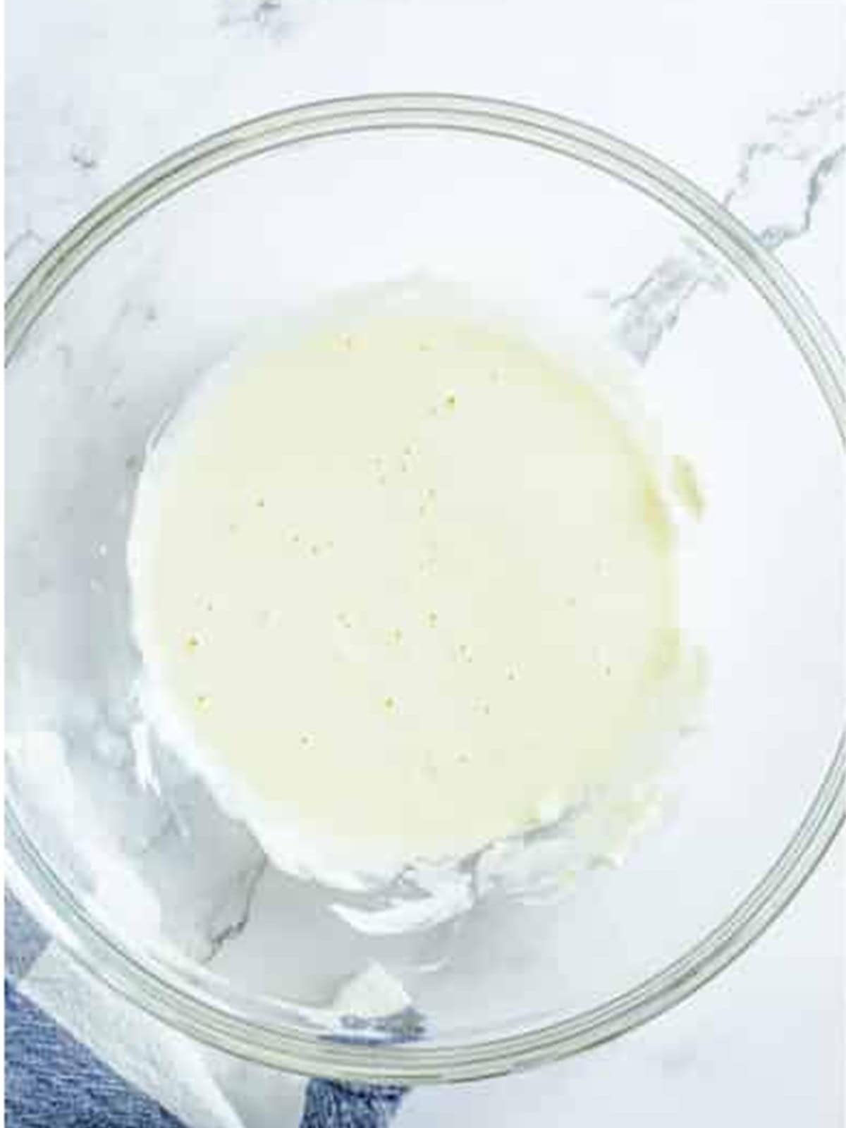 Softened cream cheese and egg mixed smooth in a glass bowl.