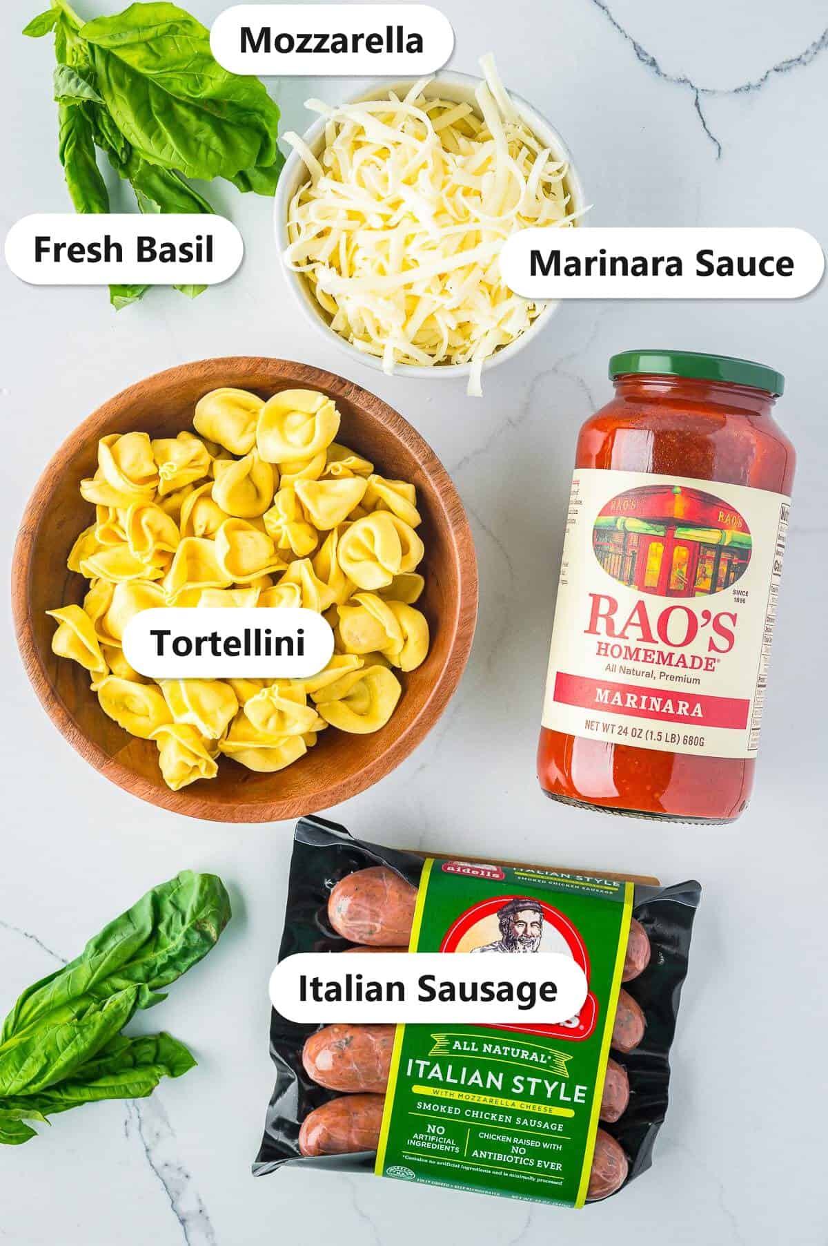 Labeled ingredients for sausage tortellini bake including fresh tortellini, Italian sausage, marinara sauce, mozzarella, and fresh basil.