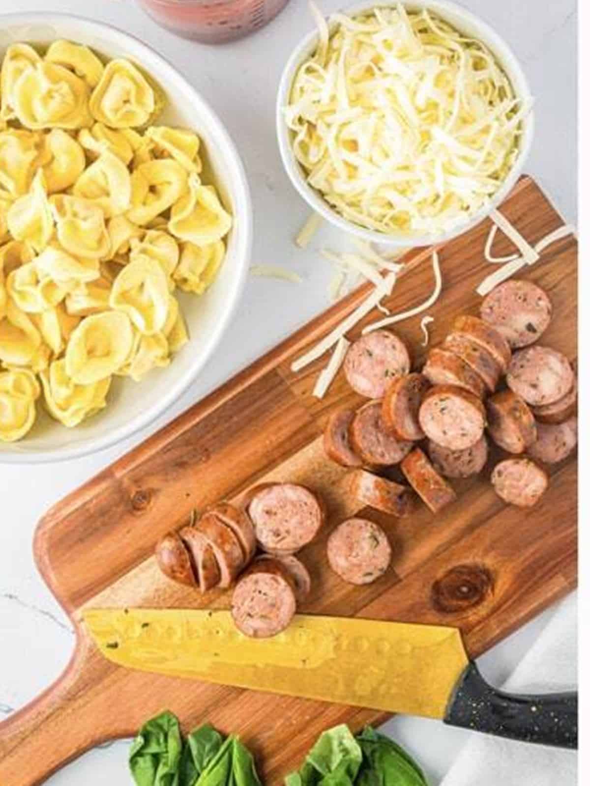 Seared Italian sausage sliced into rounds on a cutting board for sausage tortellini bake.