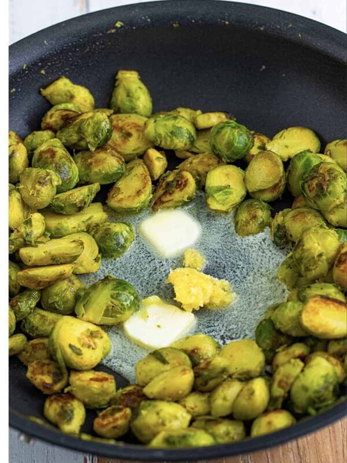 Butter melting in a well in the center of the skillet of brussel sprouts.