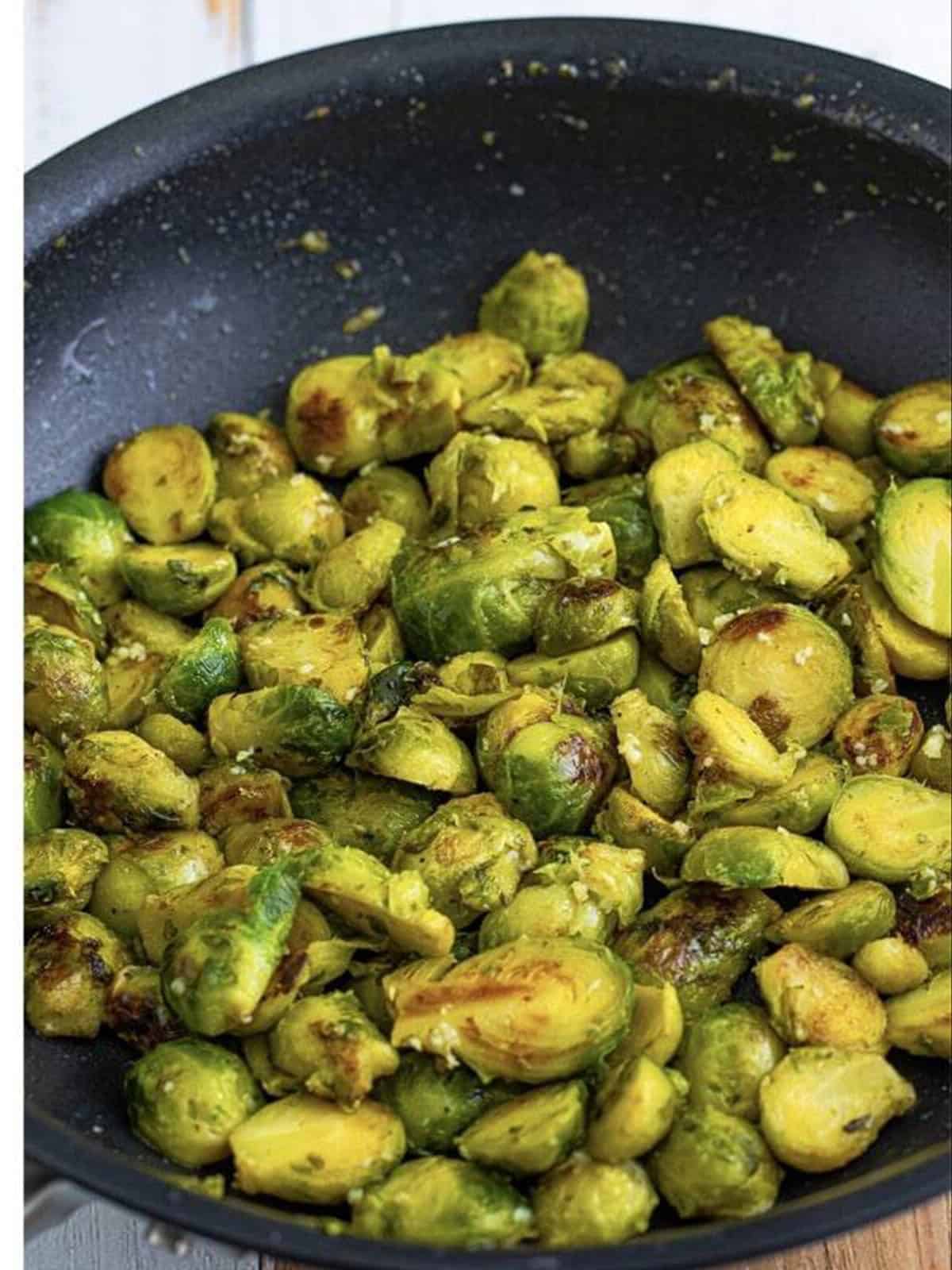 Sauteed brussel sprouts tossed with garlic butter in a skillet.