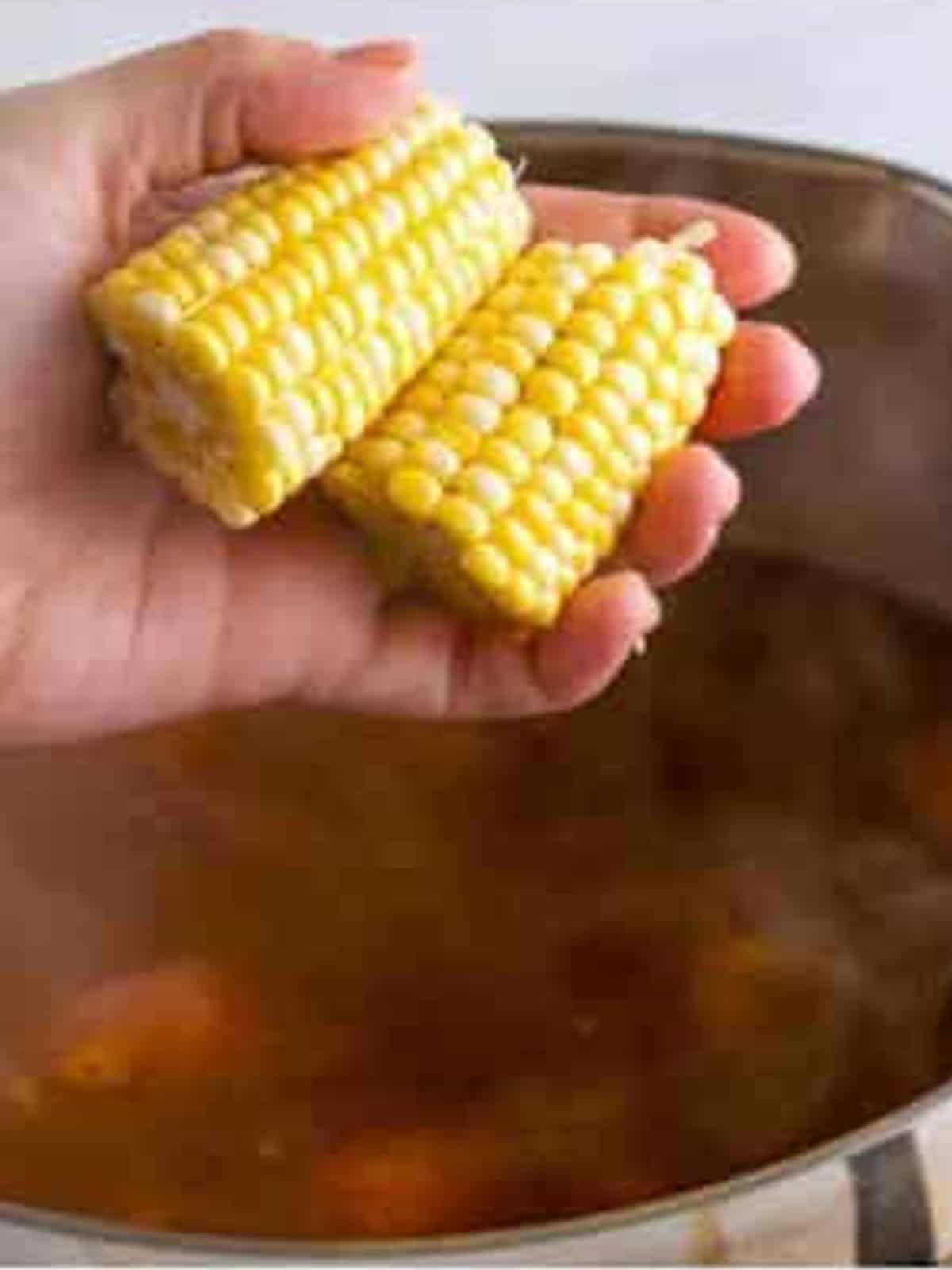 Ears of corn added to the simmering shrimp boil pot.