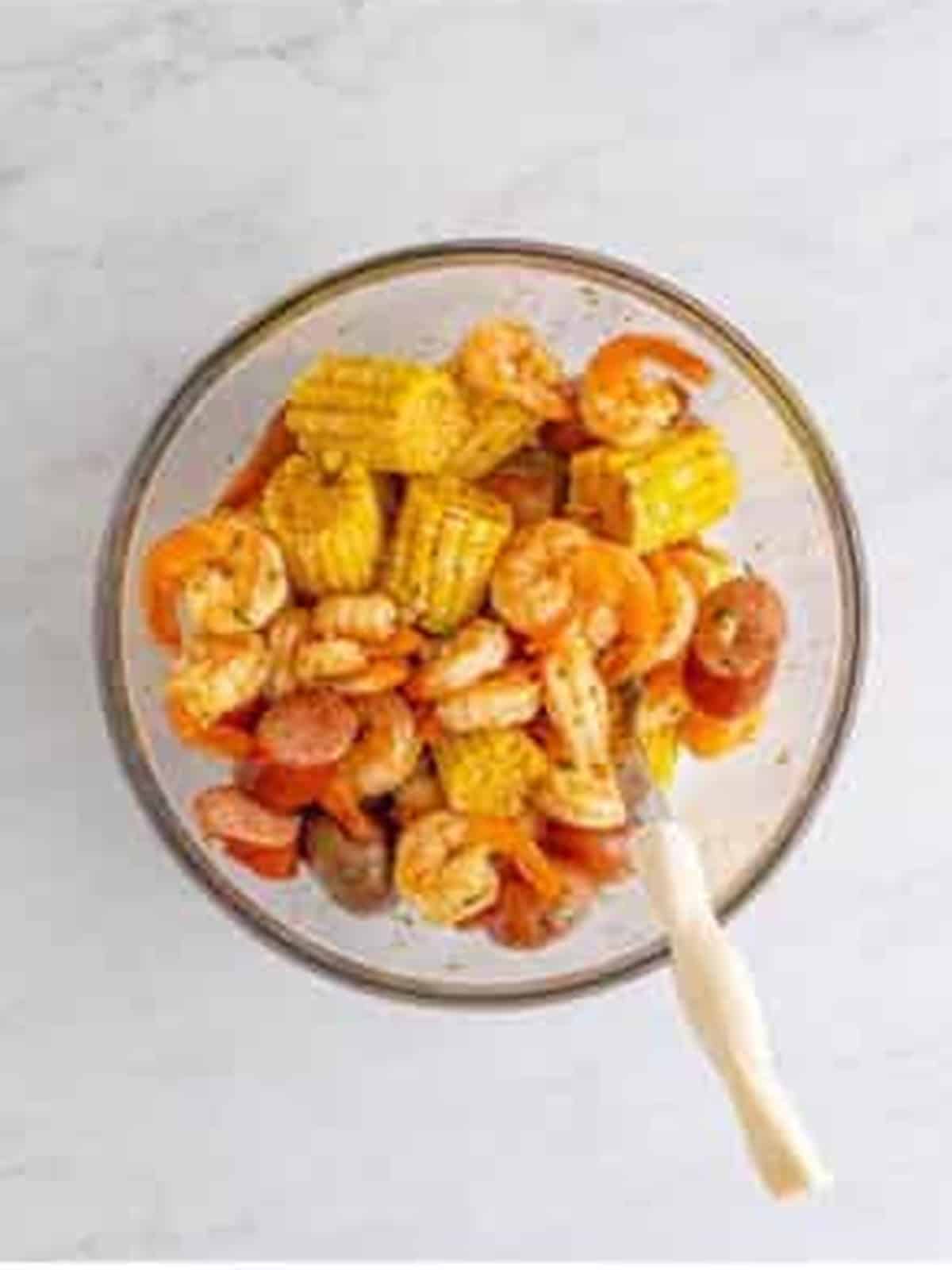 Strained shrimp boil tossed in a bowl with old bay butter sauce.