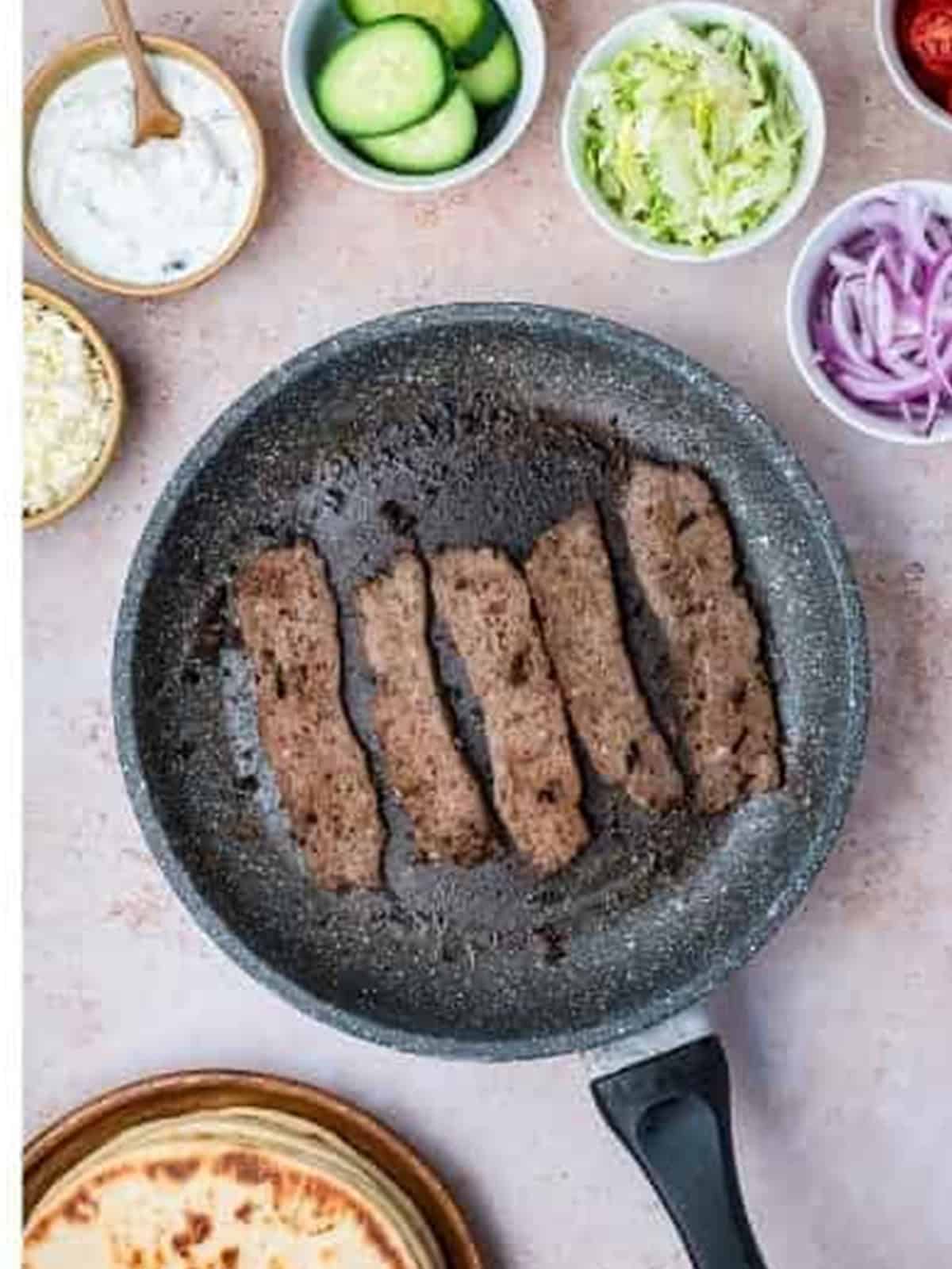 Gyro meat slices searing in a skillet until crispy