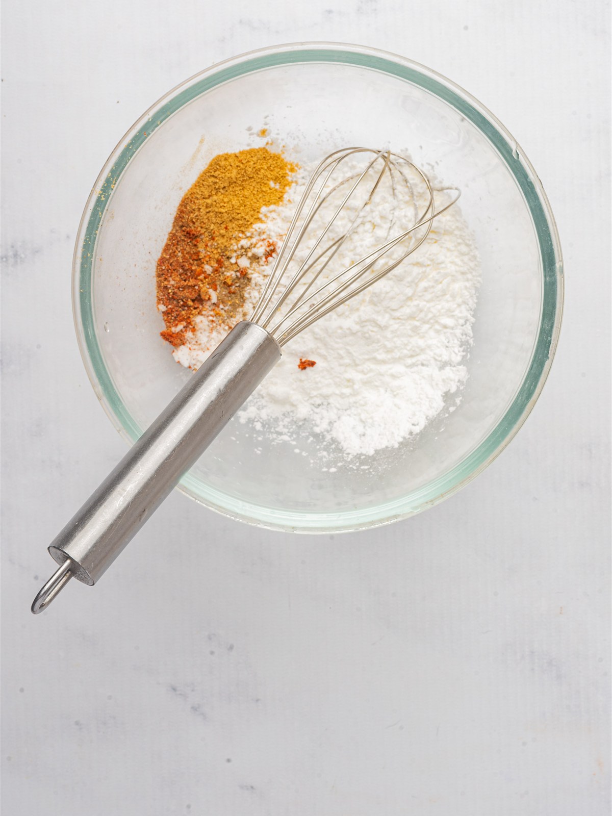 Cornstarch, salt, cayenne, and black pepper whisked together in a bowl to coat the chicken.