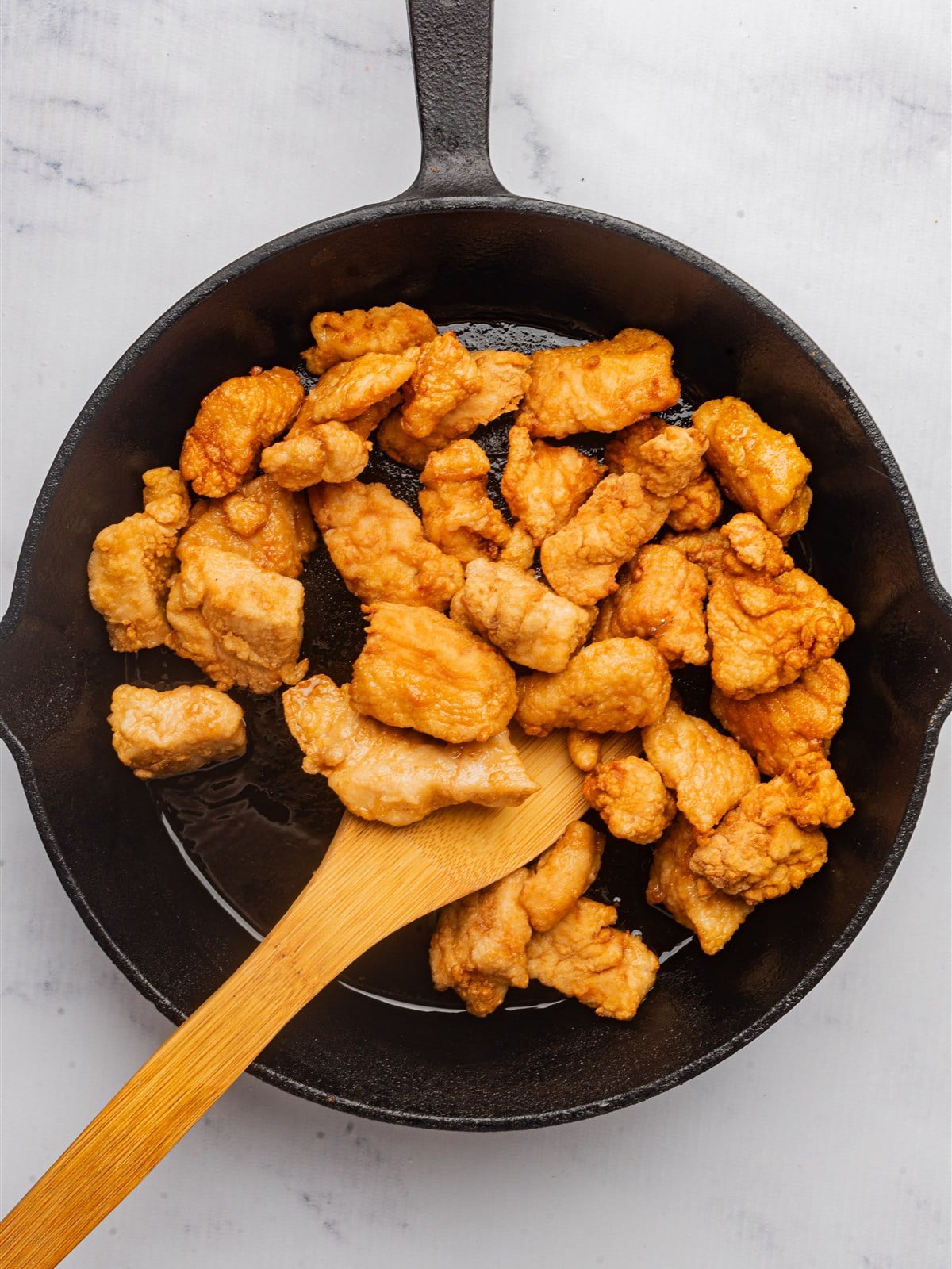 Golden pan-fried chicken pieces in a cast iron skillet.