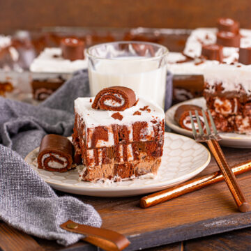 Slice of no bake Swiss roll cake on a plate with a glass of milk.